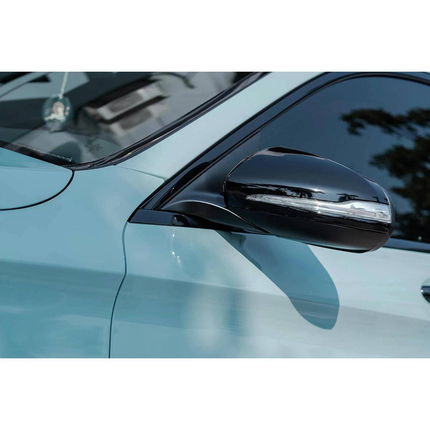 Nahaufnahme des Seitenspiegels und der Vordertür eines hellblauen Autos, die das glänzende schwarze Spiegelgehäuse und die Fensterreflektion zeigen.