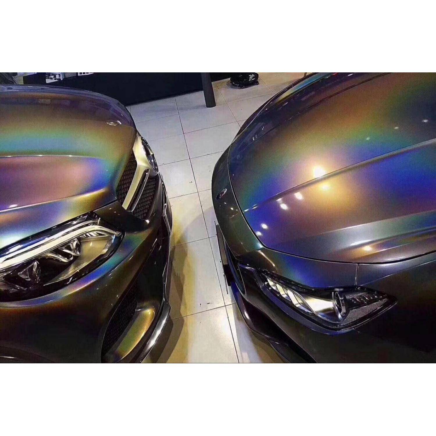 Zwei irisierend verpackte Autos sind sich auf einem Fliesenboden Stoßstange an Stoßstange gegenüber geparkt und zeigen reflektierende Regenbogenlacke auf den Motorhauben und Scheinwerfern.