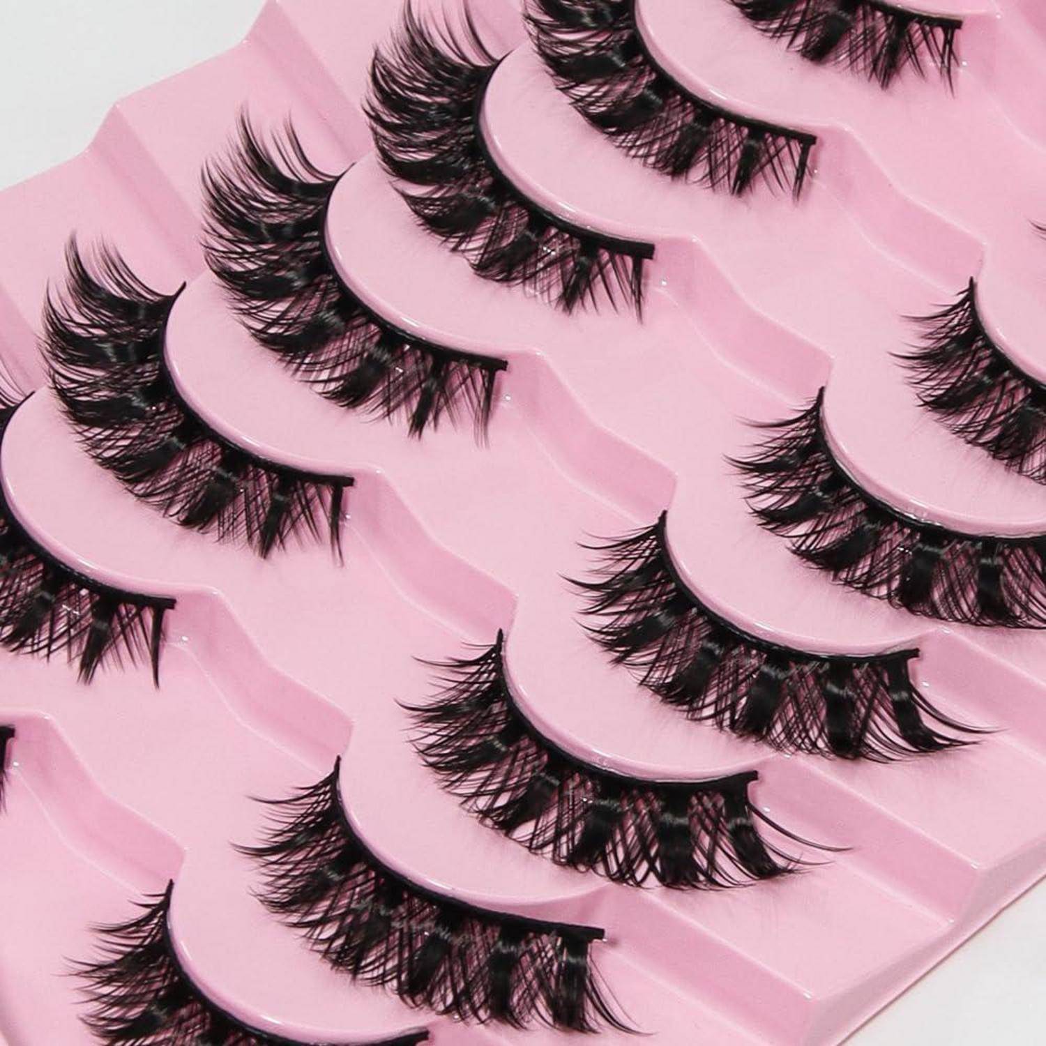 Mehrere Paare von künstlichen Wimpern, die in überlappenden rosa Kunststoffschalen angeordnet sind.