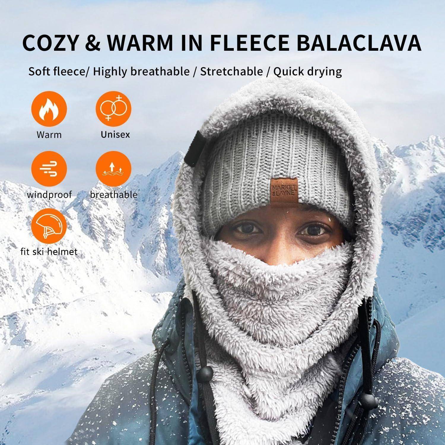 Person trägt eine graue Fleece-Sturmhaube und Mütze in verschneiten Bergen; der Anzeigentext besagt „GEMÜTLICH & WARM IN FLEECE-STURMHAUBE" und hebt Wärmeschutz, Atmungsaktivität, Windschutz, Unisex-Design und Skihelm-Passform hervor.