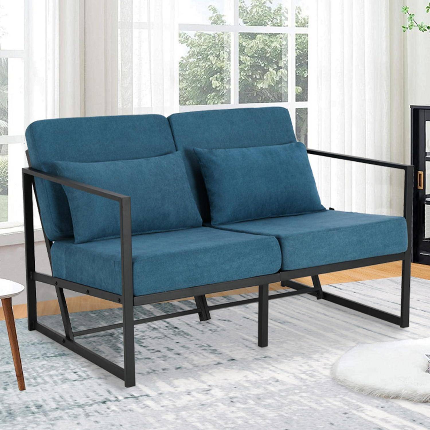 Blaues zweisitziges Sofa mit schwarzem Metallrahmen in einem hellen Raum mit Fenstern und leichten Vorhängen.