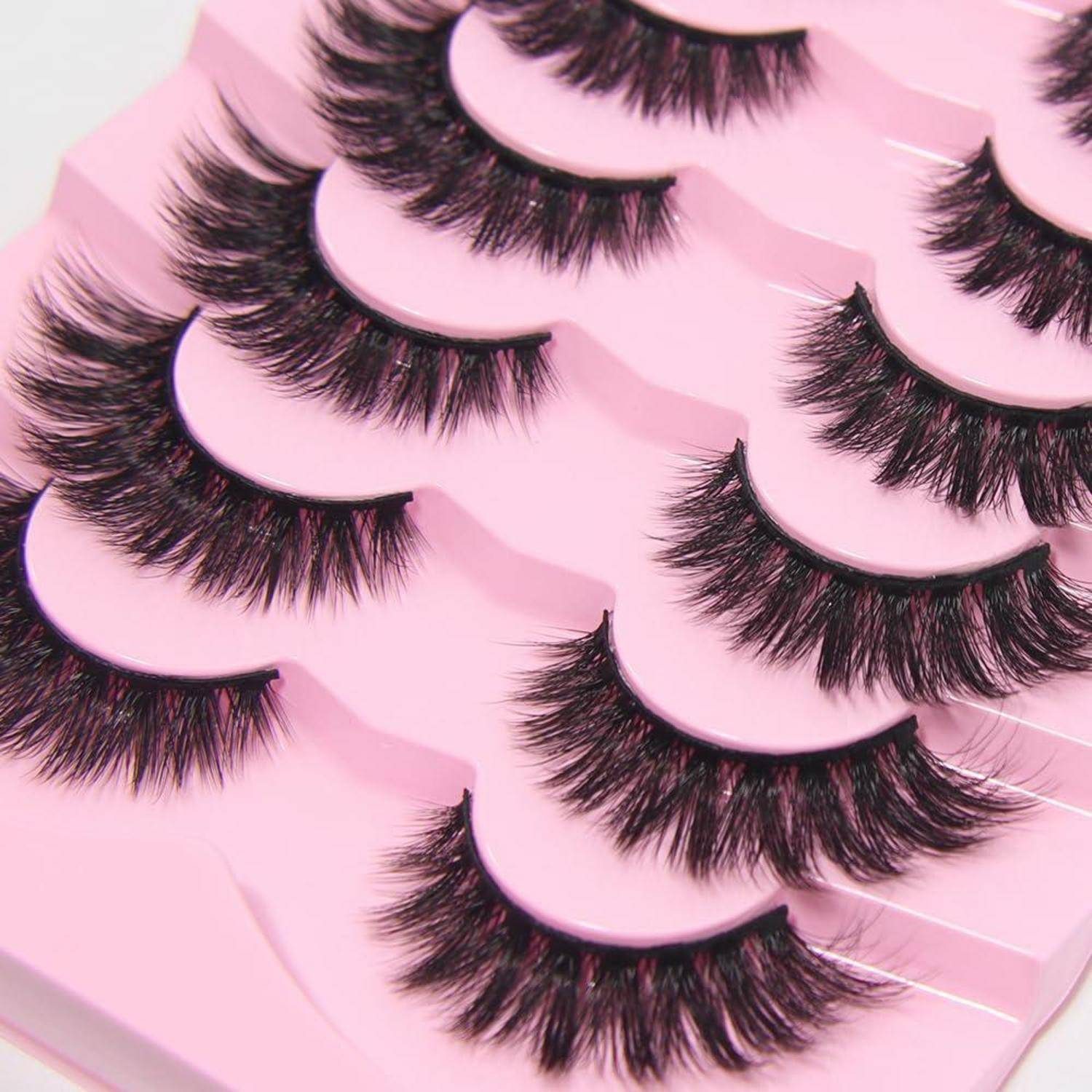 Mehrere Paare von künstlichen Wimpern, die auf rosa Haltern präsentiert werden, in einer Nahaufnahme-Produktfotografie angeordnet.