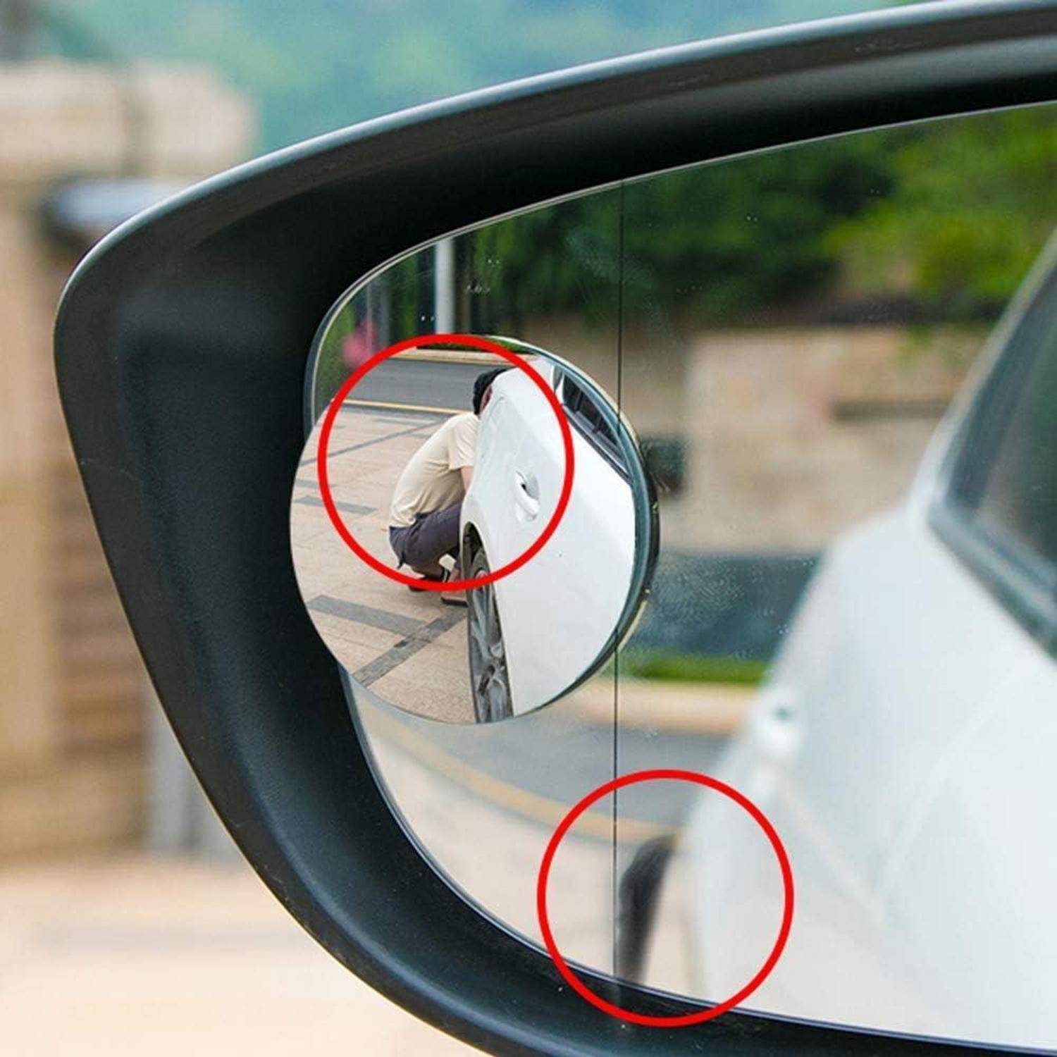 Seitenspiegel eines Autos mit hervorgehobenen toten Winkeln, die durch rote Kreise gekennzeichnet sind, und einer hockenden Person, die teilweise neben dem Fahrzeug verborgen ist.