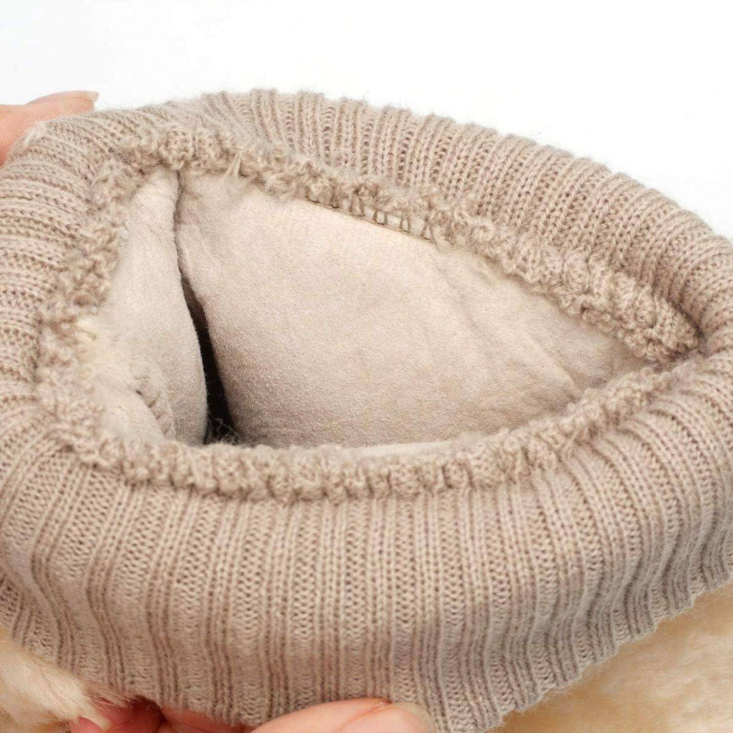 Nahaufnahme eines beigefarbenen gestrickten Pullverkragens mit weicher Fleece-Fütterung, wobei die innere Öffnung von Händen auseinandergezogen wird.