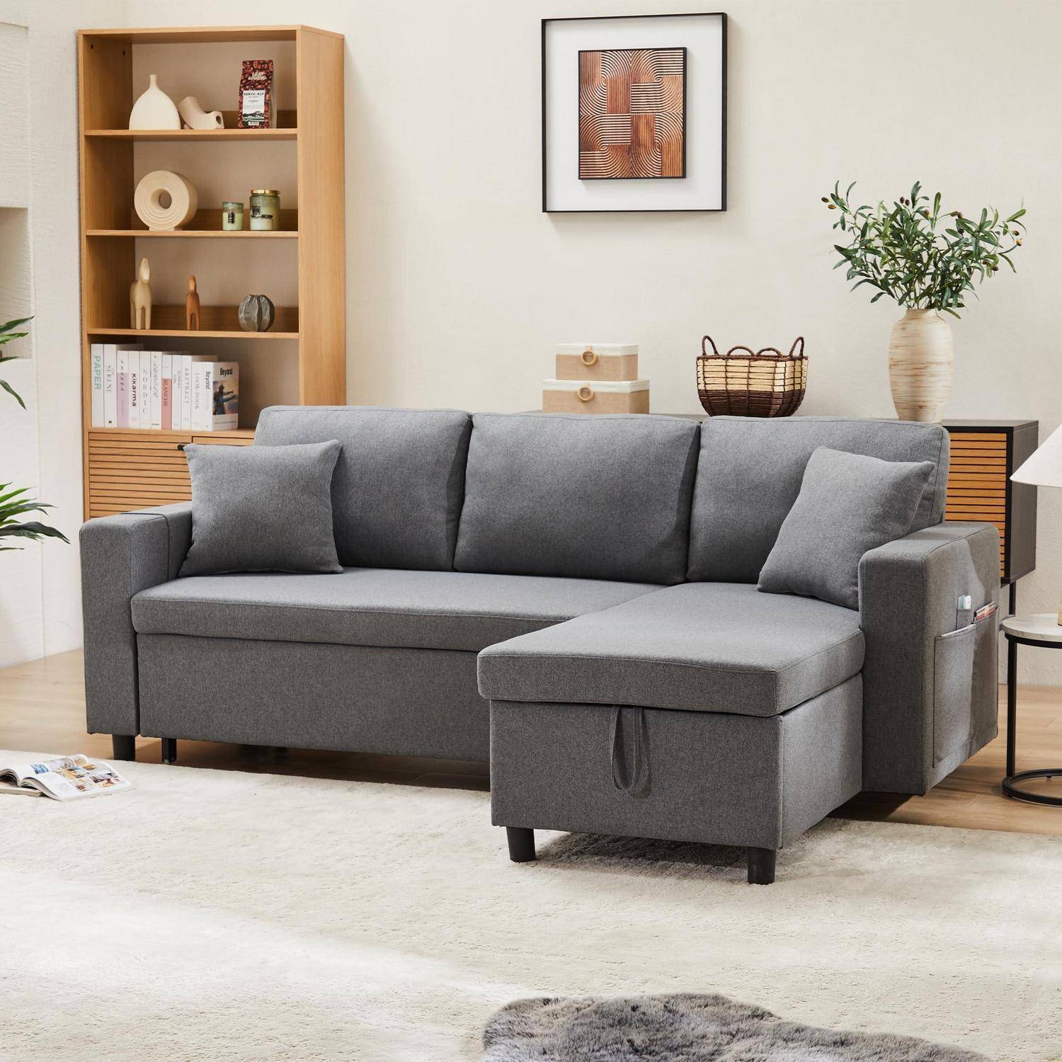 Graues L-förmiges Ecksofa mit Chaiselongue in einem modernen Wohnzimmer, mit Regalen, Wandkunst, Pflanze und hellem Teppich.