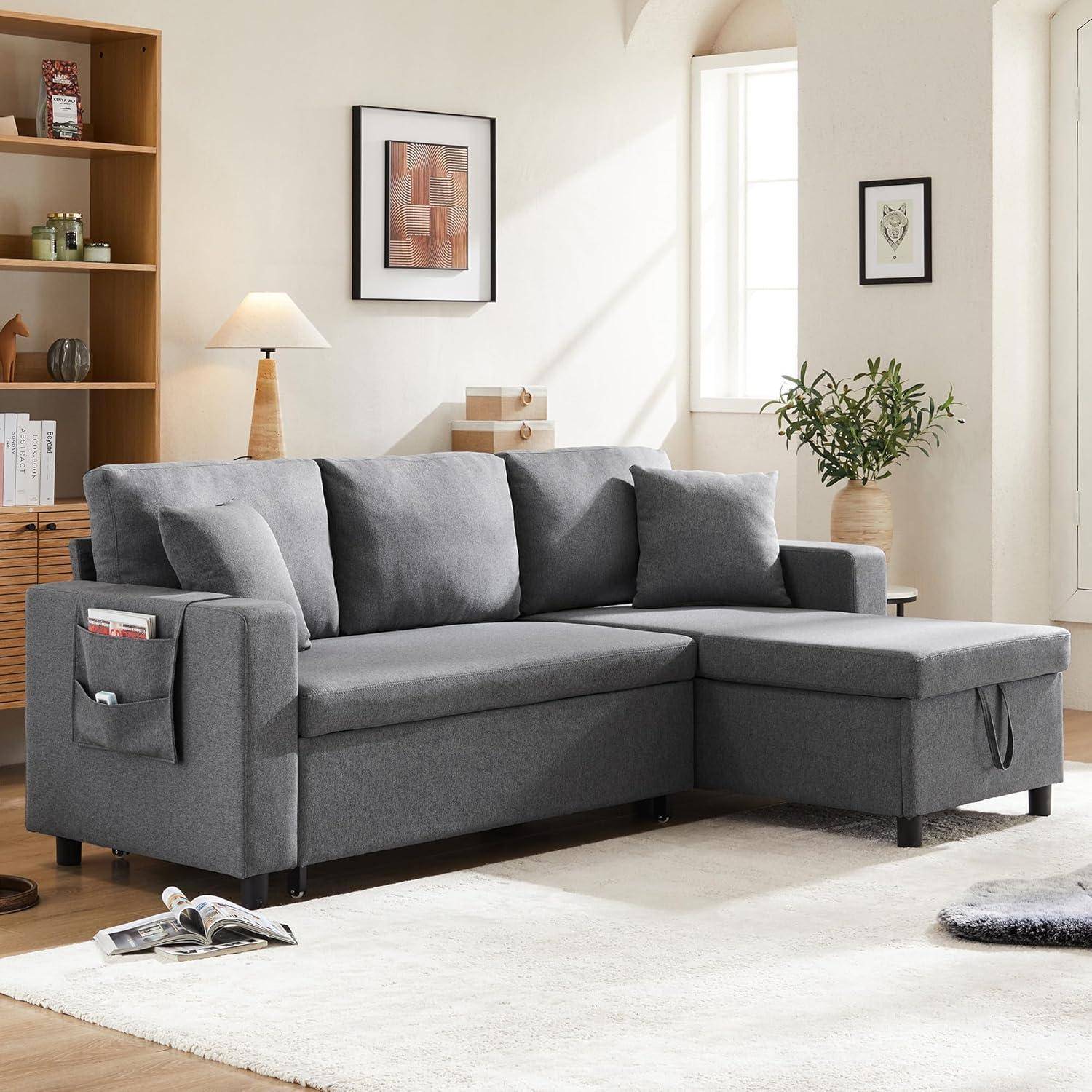 Graues Ecksofa mit Chaiselongue und Stauertaschen in einem hellen Wohnzimmer mit Bücherregal, Lampe, gerahmter Kunst und Pflanze.