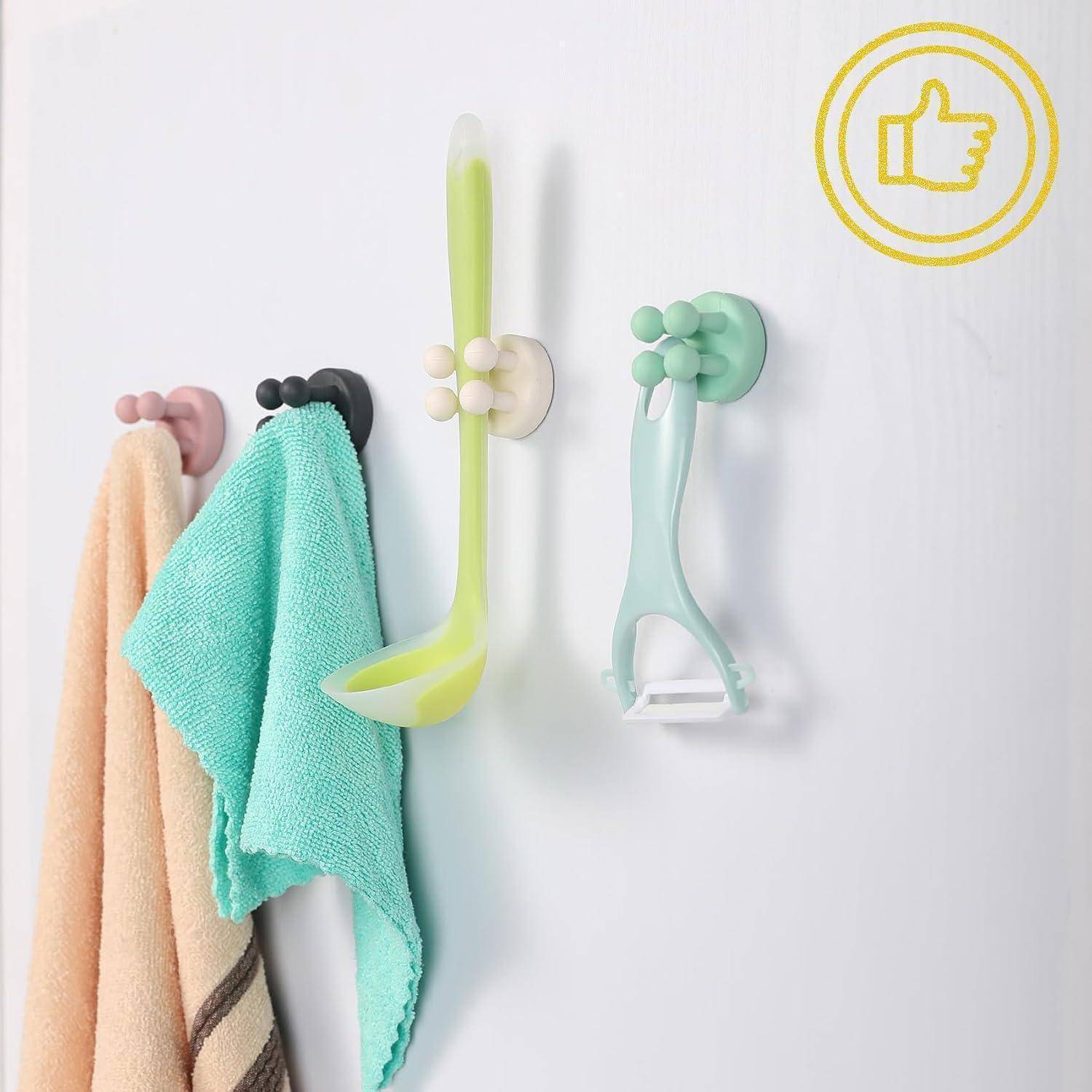 Farbenfrohe wandmontierte Haken halten Handtücher und eine langstierige Reinigungsbürste und zeigen platzsparende Aufbewahrung im Badezimmer oder in der Küche.