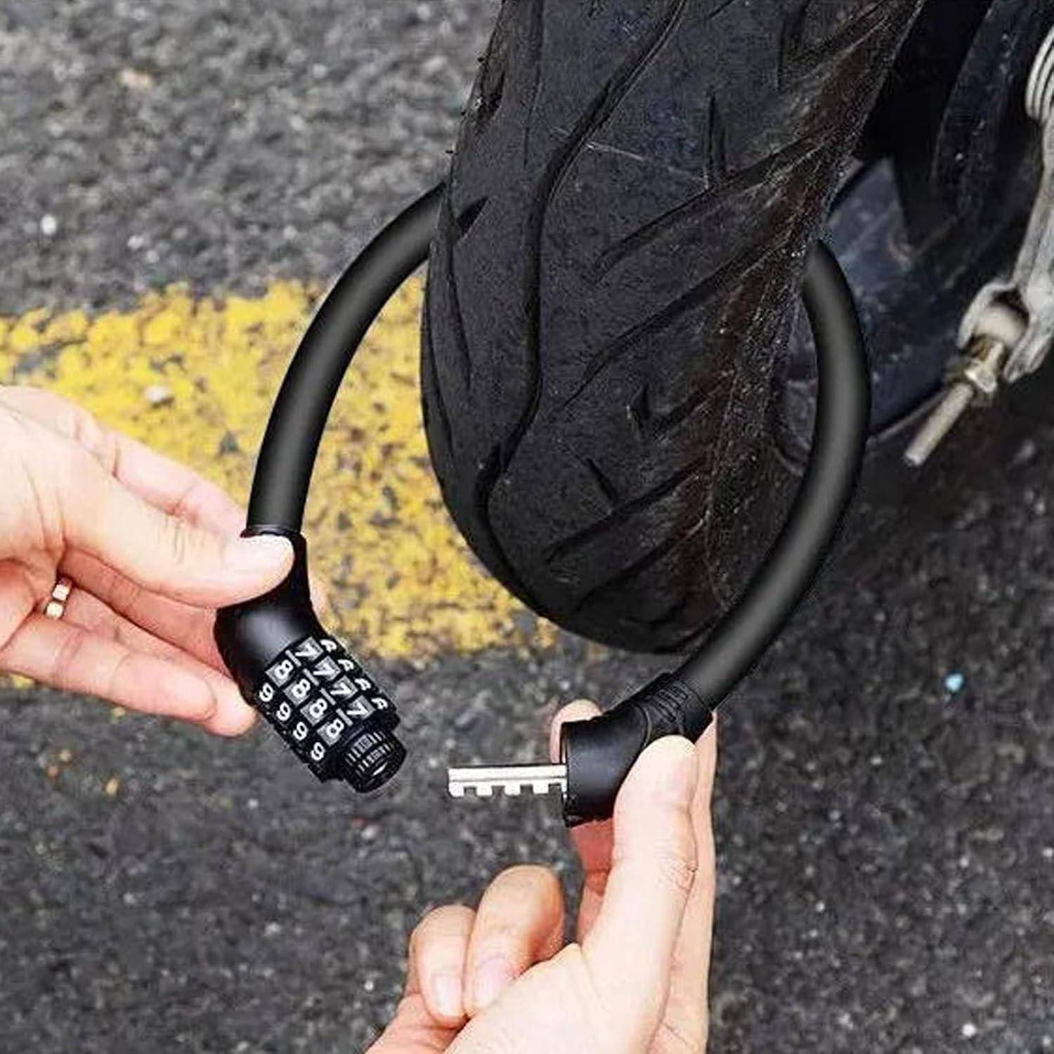 Hände halten ein aufgerolltes Kombinationszahlenschloss für Fahrräder um einen Motorradreifen, wobei an einem Ende ein vierstelliges Zahlenkombinationsschloss und am anderen Ende ein Metallstecker sichtbar sind.