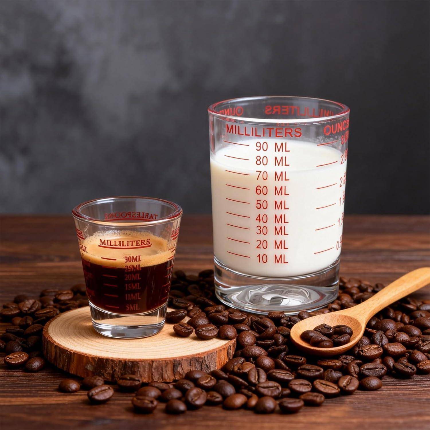 Kaffeebohnen, eine Tasse dunkler Kaffee und ein Glas Milch mit Messskalen auf einem Holztisch.