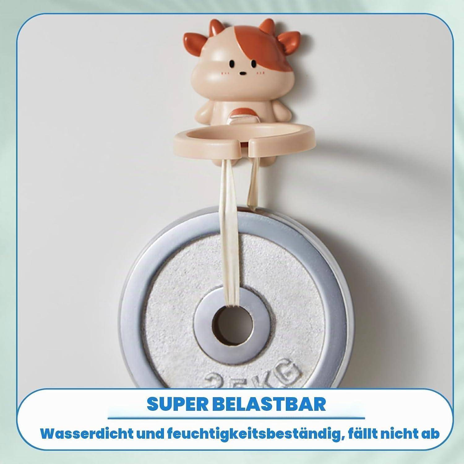 Spielzeug-Saugnapfhaken mit einem Cartoon-Kuh-Halter über einer kreisförmigen Fläche; Text besagt „SUPER BELASTBAR