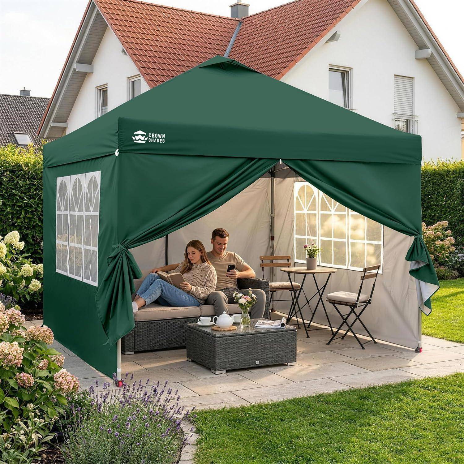 Zwei Menschen entspannen sich in einem grünen Gartenpavillon mit Vorhängen, einem Sofa und einem Terrassentisch-Set im Hinterhof.