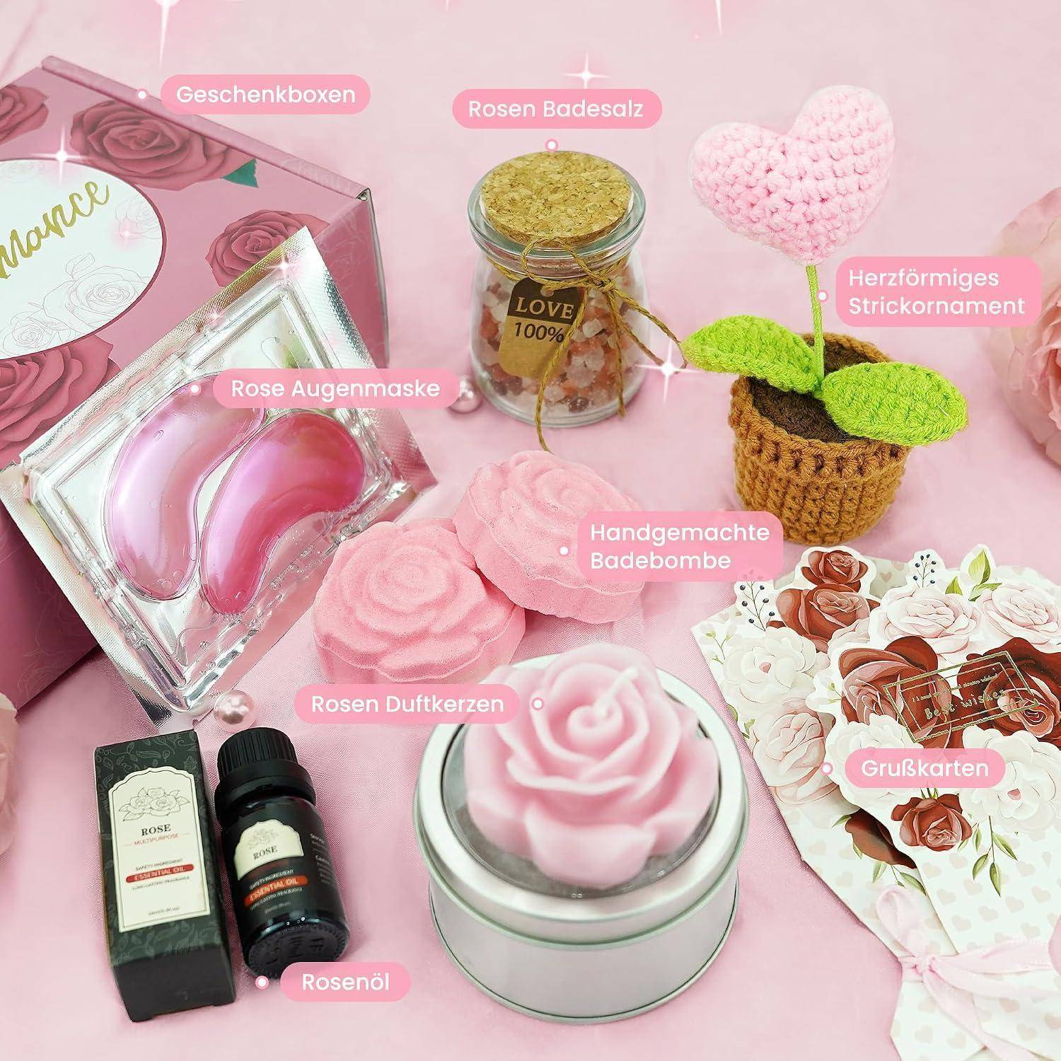 Rosa Rosen-Geschenkset mit beschrifteten Artikeln: Geschenkbox, Rosen-Badesalz, Augenklappe, handgemachte Badebombe, duftende Kerze, Rosenöl, gestrickte Herzornament und Grußkarten auf rosa Hintergrund.