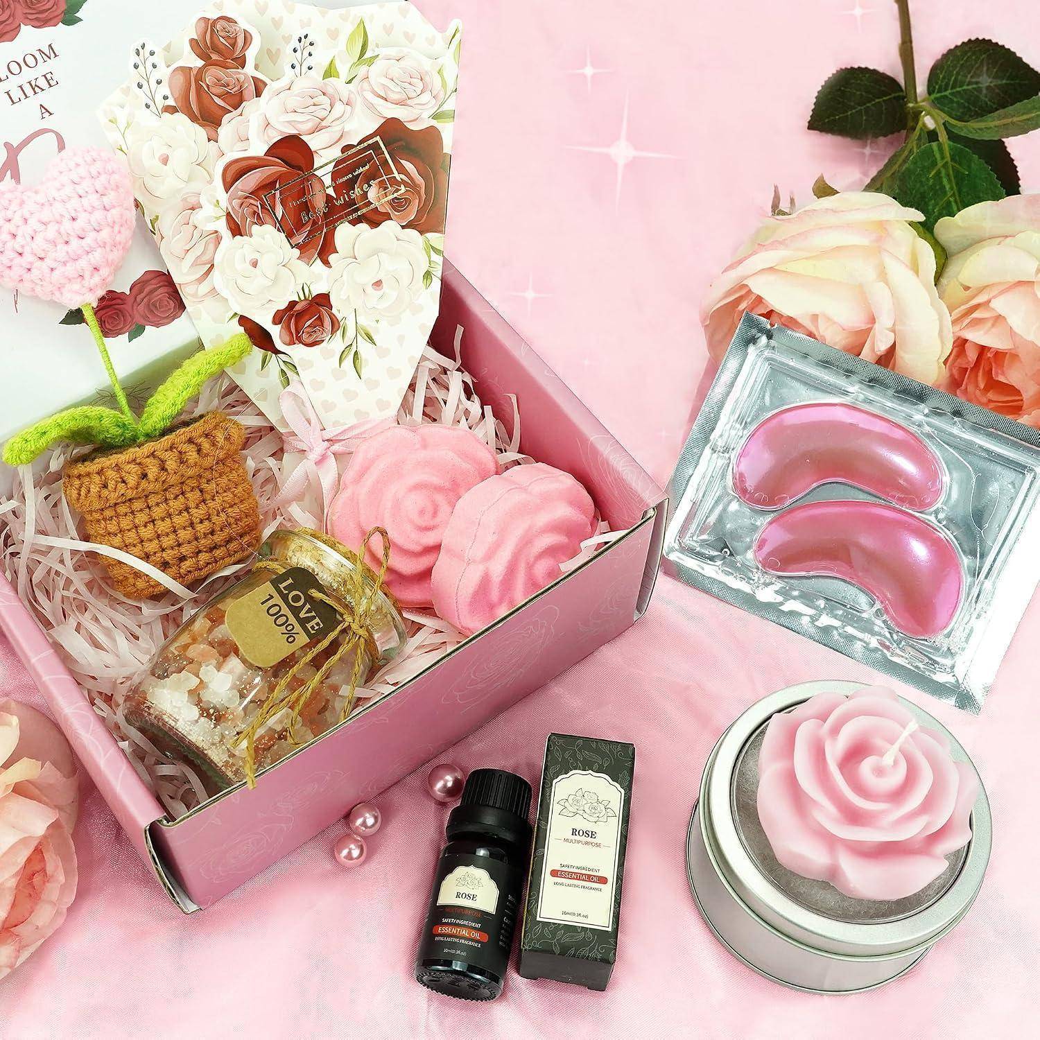 Rosa Geschenkbox mit Rosendekoration, Spa-Augenpflaster, Kerzen, Seife und kleine Flaschen auf rosa Hintergrund arrangiert.