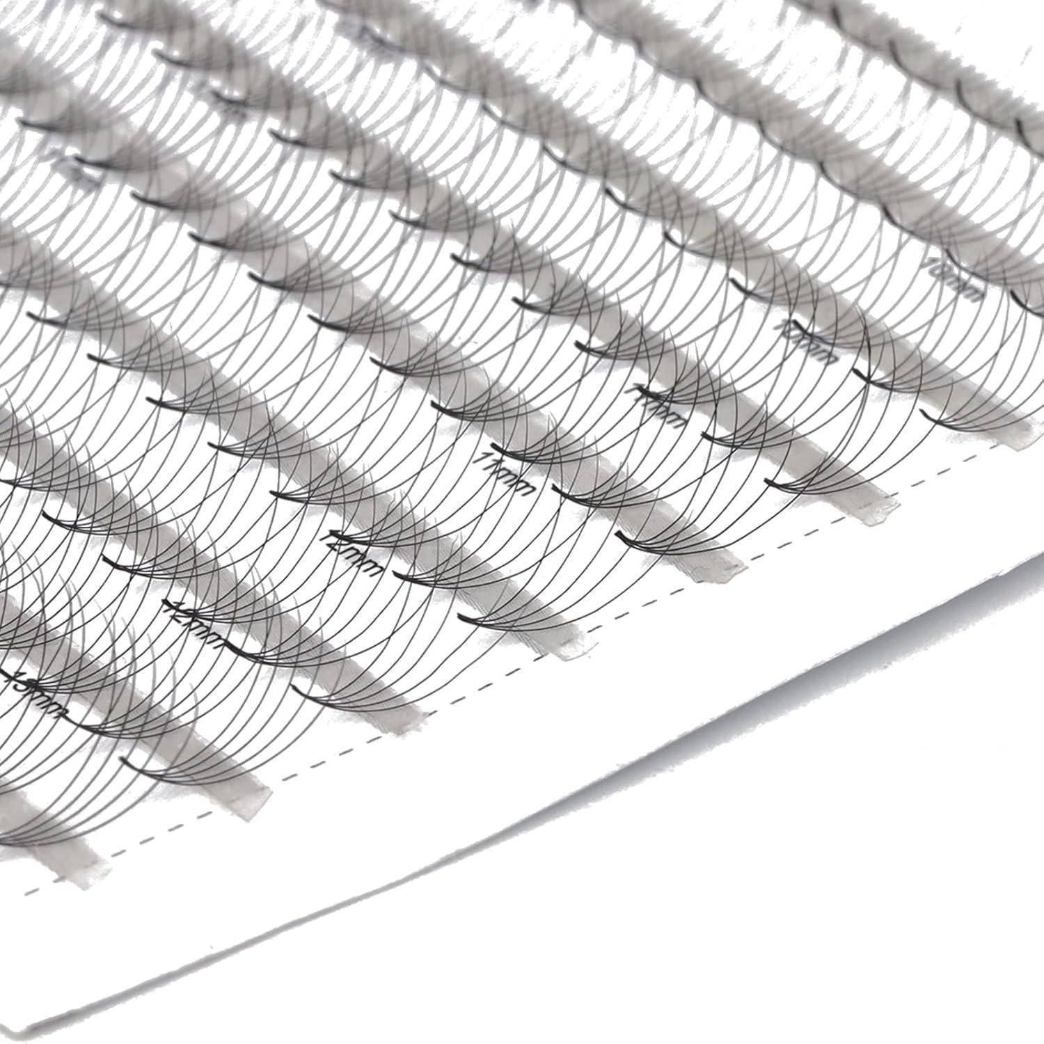 Nahaufnahme eines Tabletts mit künstlichen Wimpernverlängerungen, die in Reihen auf weißem Untergrund angeordnet sind.
