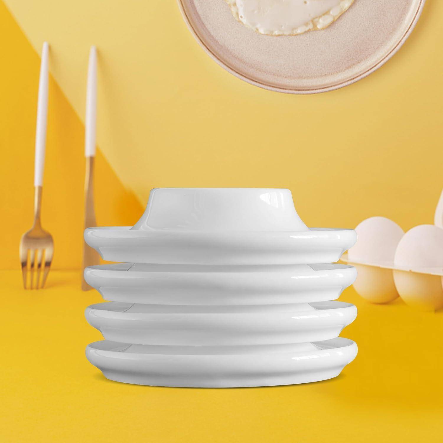 Stapel weißer Teller mit einer Tasse oben drauf, auf einem gelben Tisch angeordnet mit Besteck, Eiern und einem beigefarbenen Hut im Hintergrund.