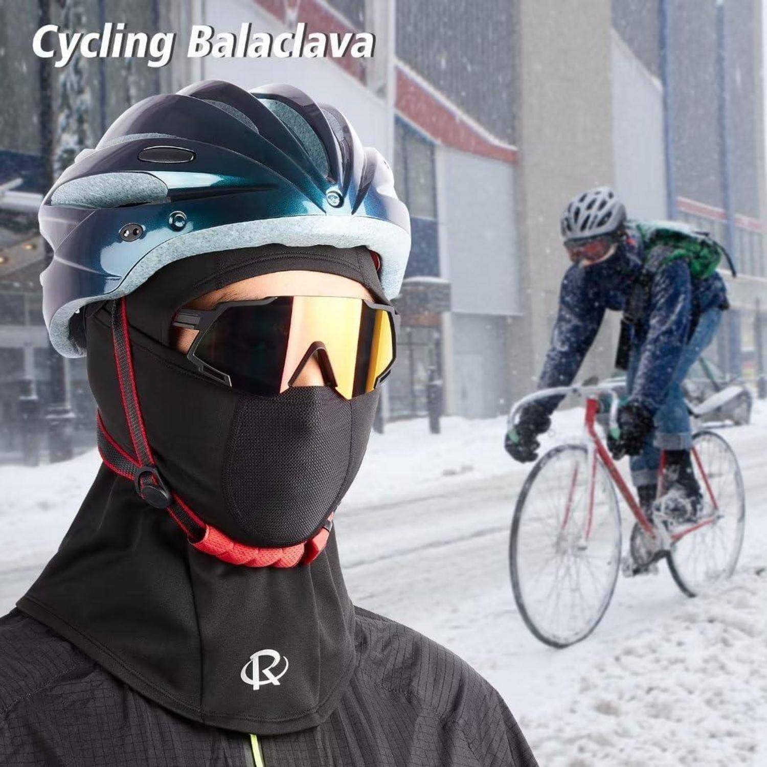 Radfahrer in Winterkleidung mit Helm, Schutzbrille und Gesichtsschutz auf verschneiter Straße; ein weiterer Fahrer fährt hinter ihm.