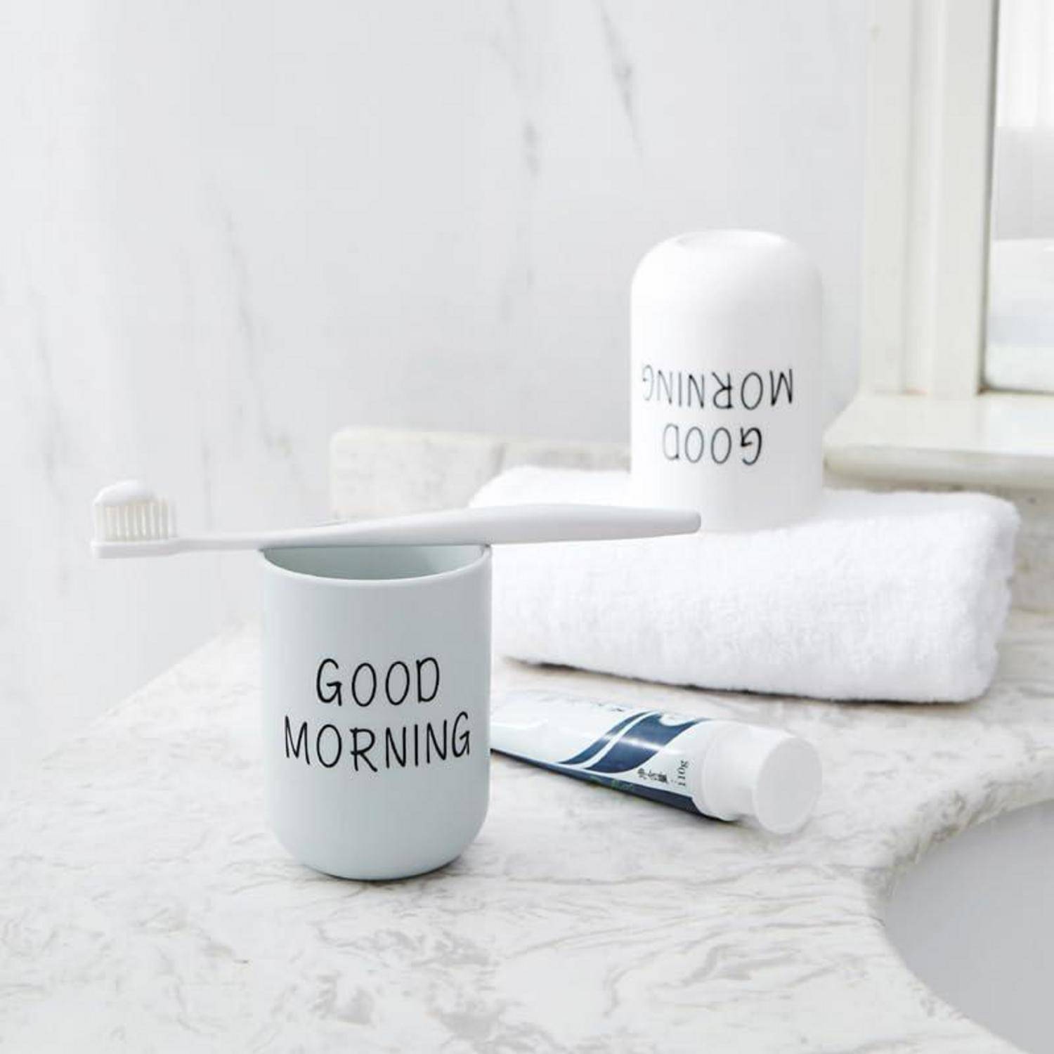 Badezimmer-Waschtisch mit einer Zahnbürste, die auf einer Tasse mit der Aufschrift „GOOD MORNING