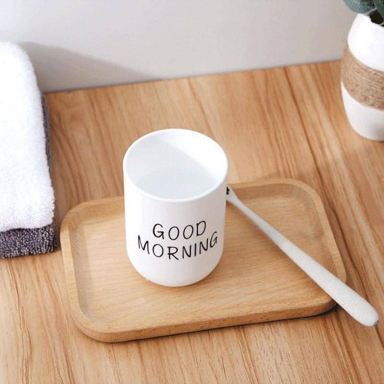 Weiße Tasse auf einem Holztablett mit der Aufschrift „GOOD MORNING