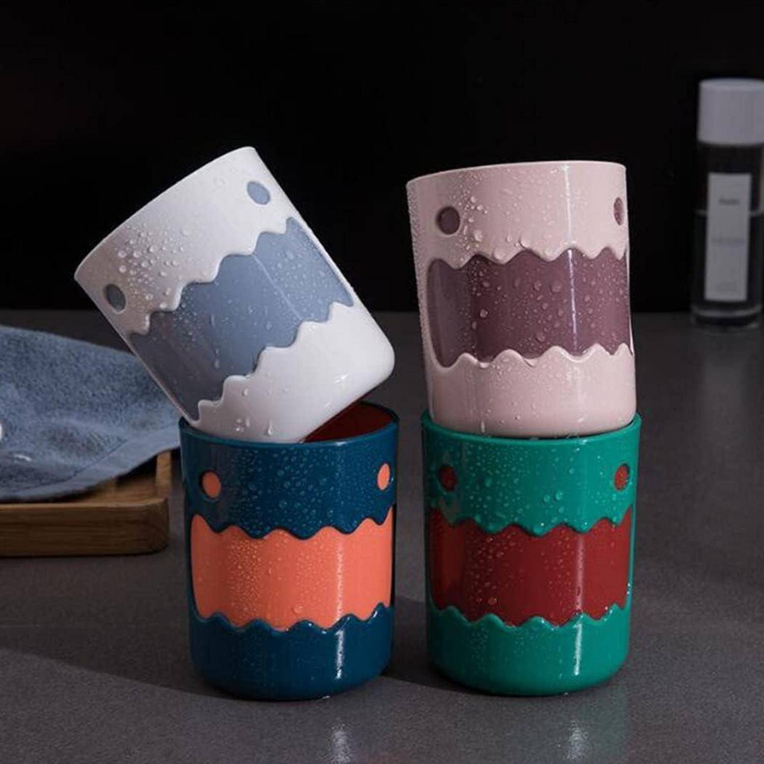 Gestapelte, farbenfrohe Keramiktassen mit welligen Punktmuster-Designs, die auf einer dunklen Oberfläche angeordnet sind, mit einer Tasse, die diagonal oben aufgestellt ist.