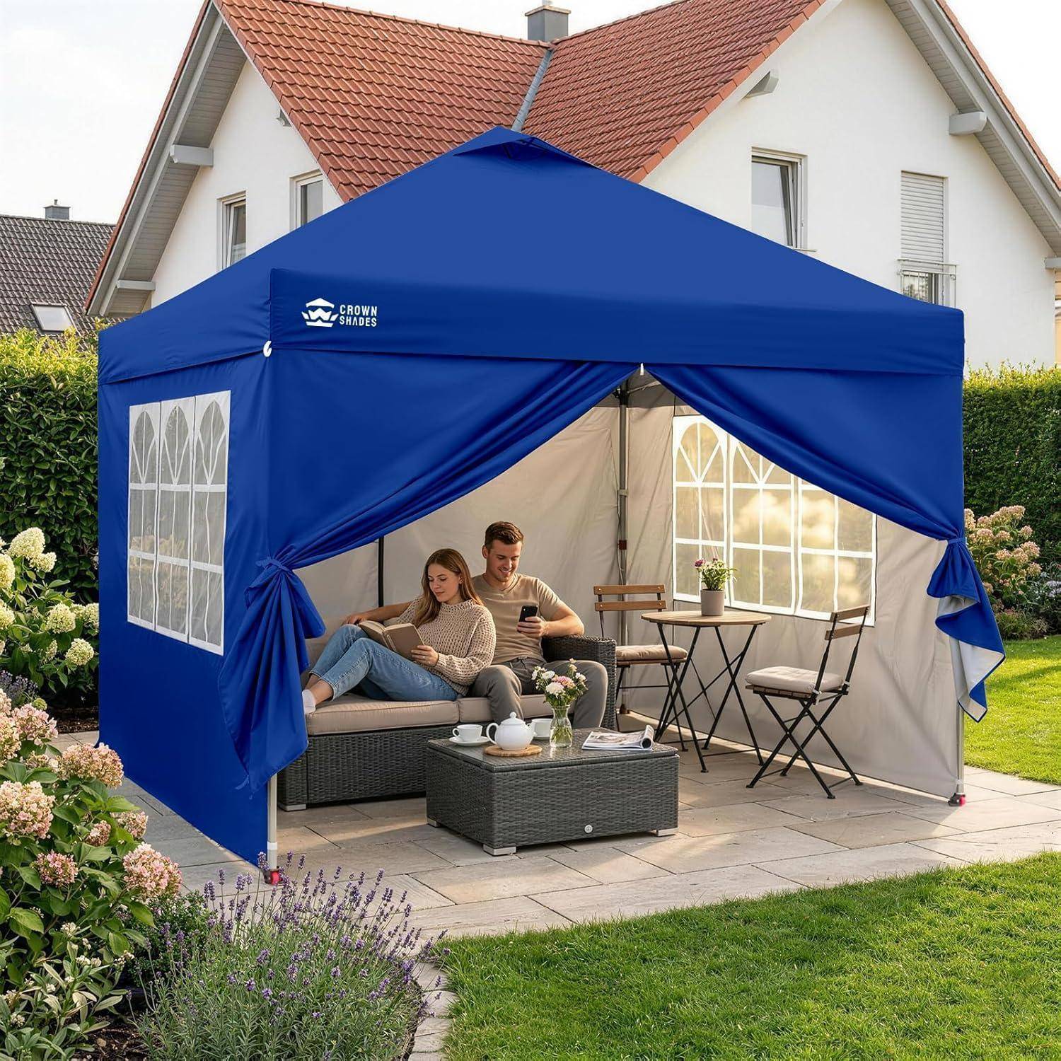 Blaues Pop-up-Zelt im Hinterhof, mit zwei Personen, die auf einem Sofa entspannen, und einem kleinen Tisch und Stühlen im Inneren.