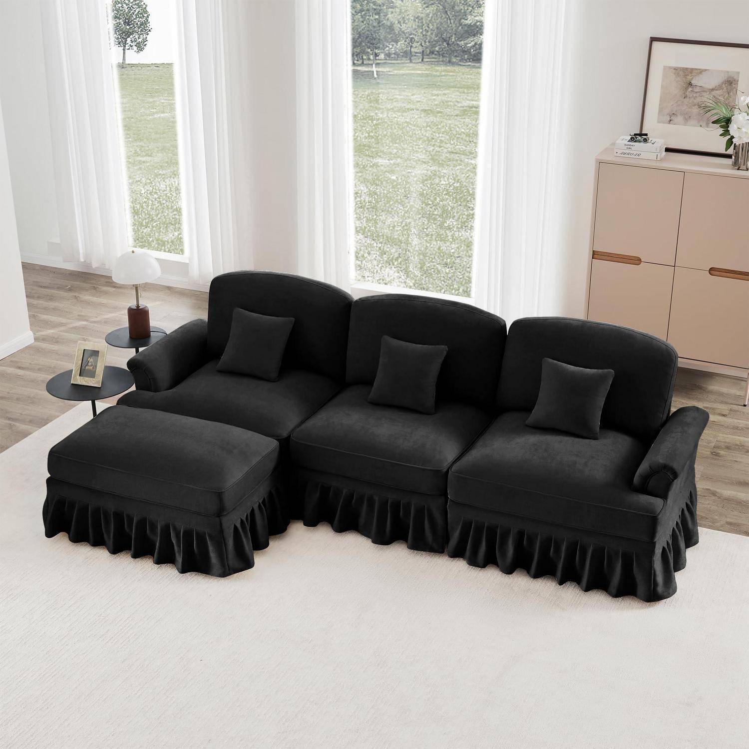 Schwarzes Ecksofa mit Chaiselongue, drei Dekokissen und Beistelltisch in einem hellen Wohnzimmer mit großen Fenstern und einem Schrank.