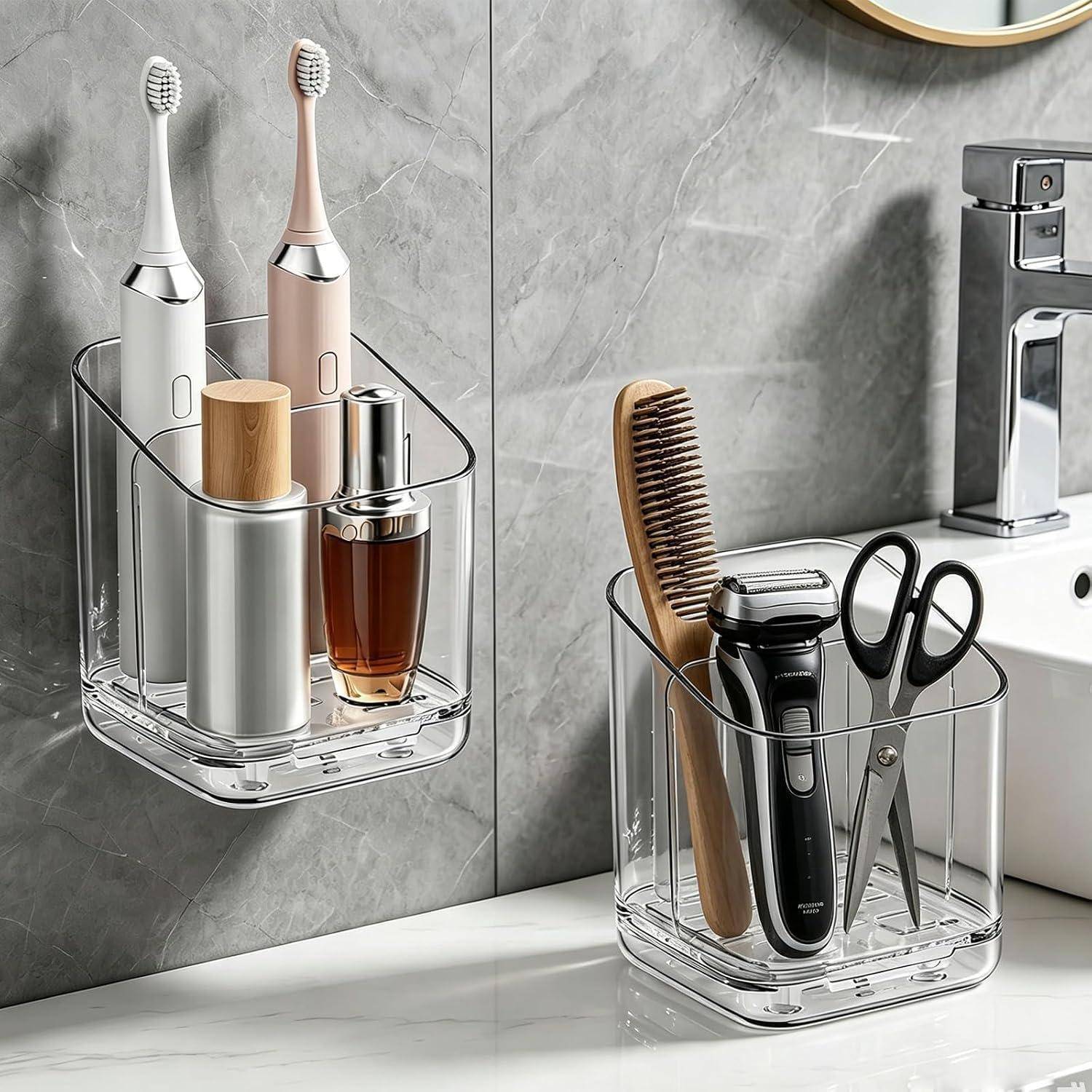 Zwei klare, an der Wand montierte Badezimmerorganizer halten elektrische Zahnbürsten, Toilettenartikel, eine Haarbürste, einen Rasierer und eine Schere neben einem Waschbecken.