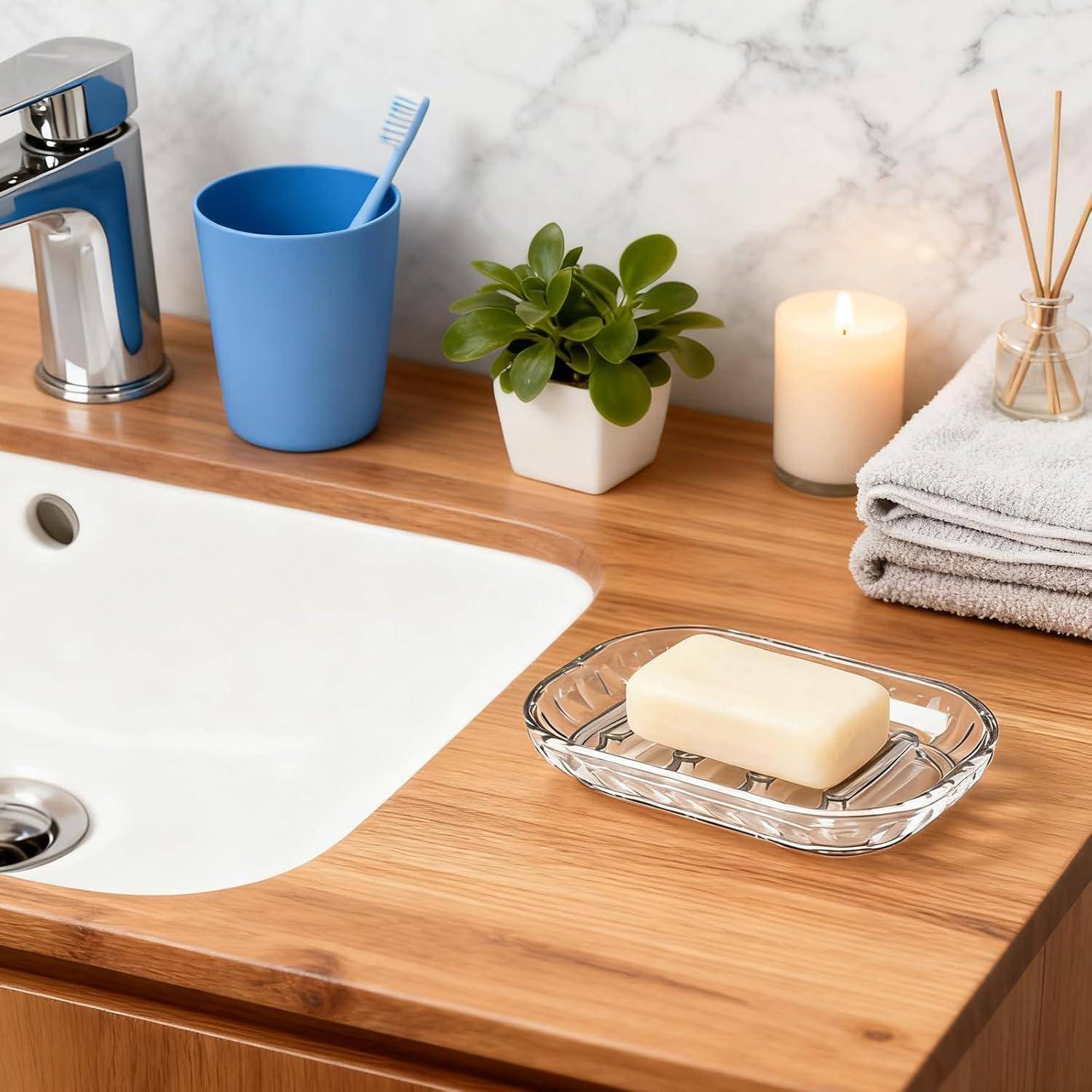 Ein sauberes Badezimmer-Waschbecken mit Becken, Seifenschale, Zahnbürstenbecher, Pflanze, Kerze, Handtüchern und einem Raumduft-Diffusor auf einer Holzarbeitsplatte.