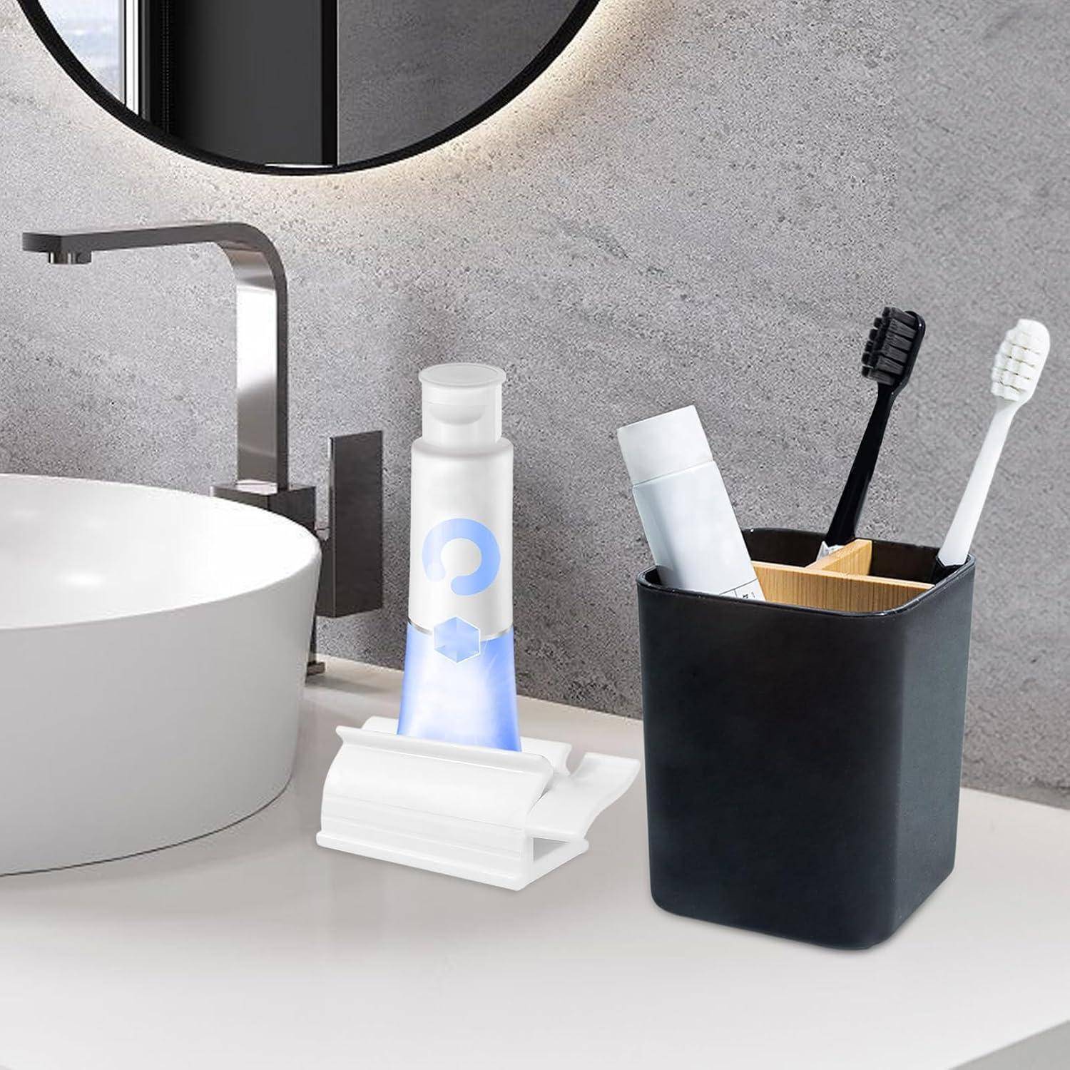 Badezimmerablage mit einem weißen Waschbecken, modernem Wasserhahn, Zahnbürsten in einem schwarzen Halter und einer Zahnpastatube, die auf einem kleinen weißen Ständer steht.