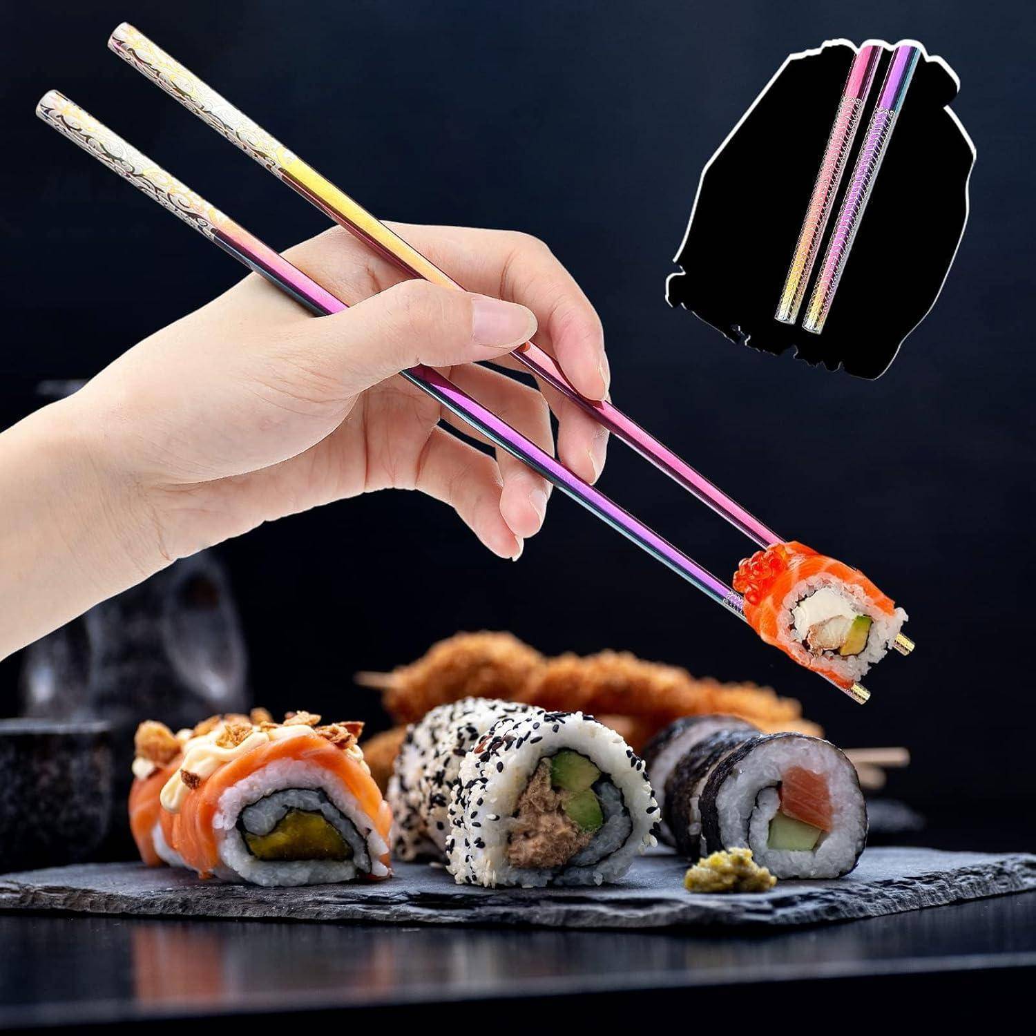 Hand, die mit bunten Stäbchen eine Sushi-Rolle über assortiertem Sushi auf einem Serviertablett hebt, mit einer Vergrößerung, die das Stäbchen-Set zeigt.