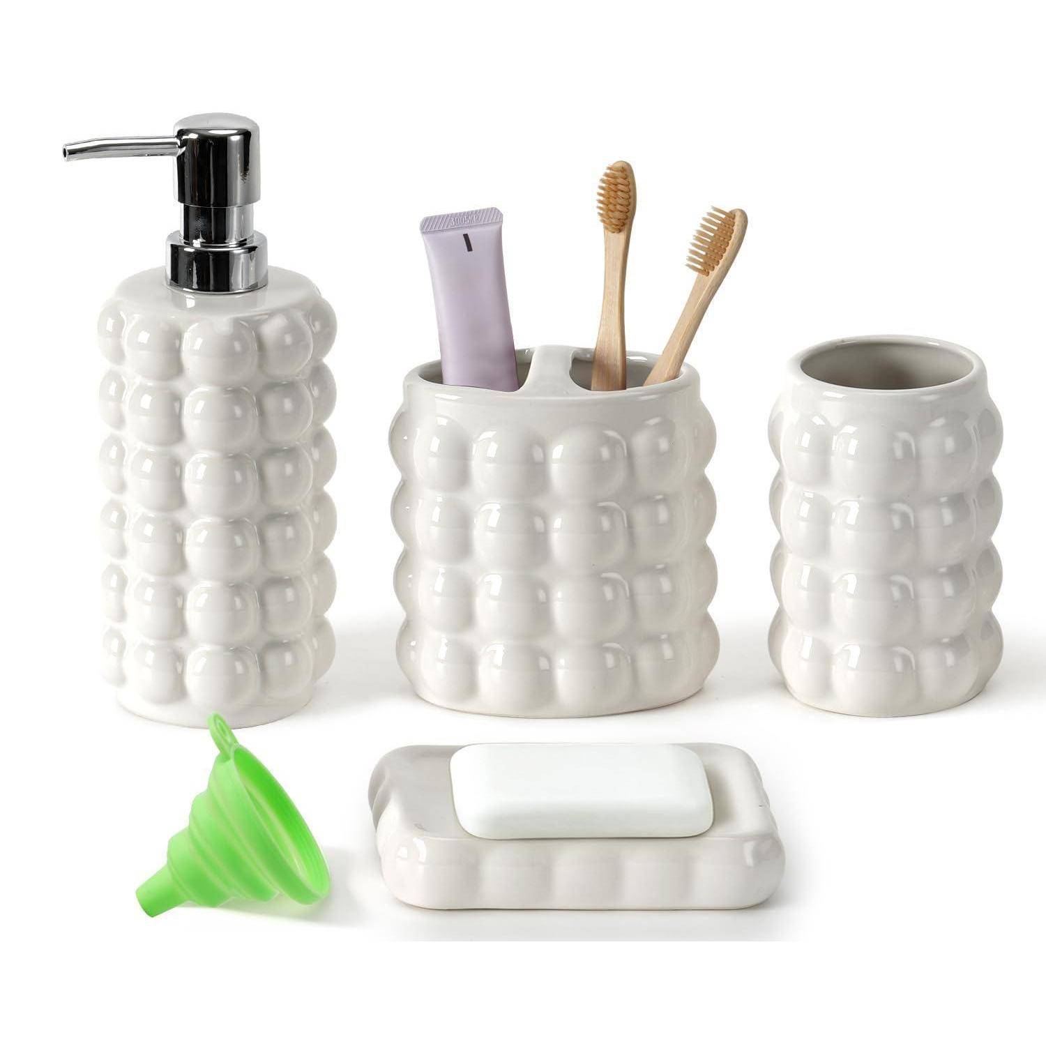 Weißes Keramik-Badezimmerset mit Blasentextur: Seifenspender, Zahnbürstenhalter mit Gegenständen, Becher, grüner Trichter und Seifenschale auf weißem Hintergrund.