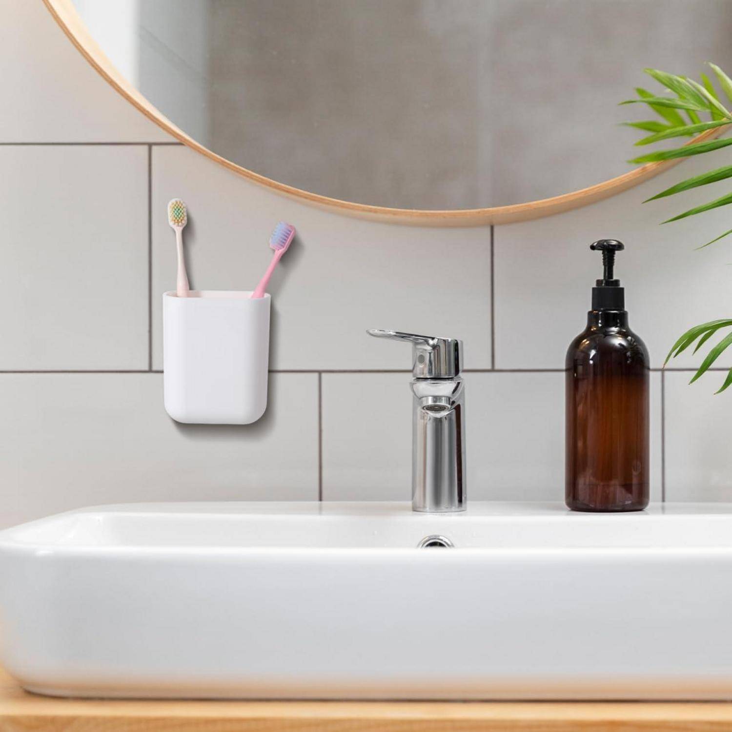 Modernes Badezimmer-Waschbecken mit einem wandmontierten Spiegel, zwei Zahnbürsten in einem Halter und einem Seifenspender auf der Arbeitsplatte.
