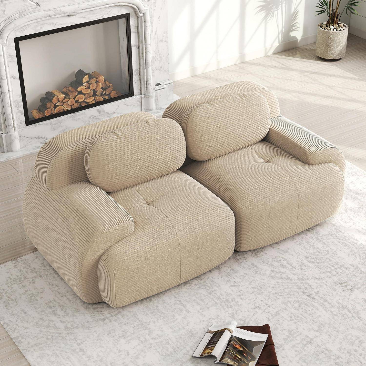 Beige modulares Zweisitzer-Sofa mit abgerundeten Kissen in einem hellen Wohnzimmer neben einem Kamin, gezeigt mit einer Zeitschrift auf dem Teppich.