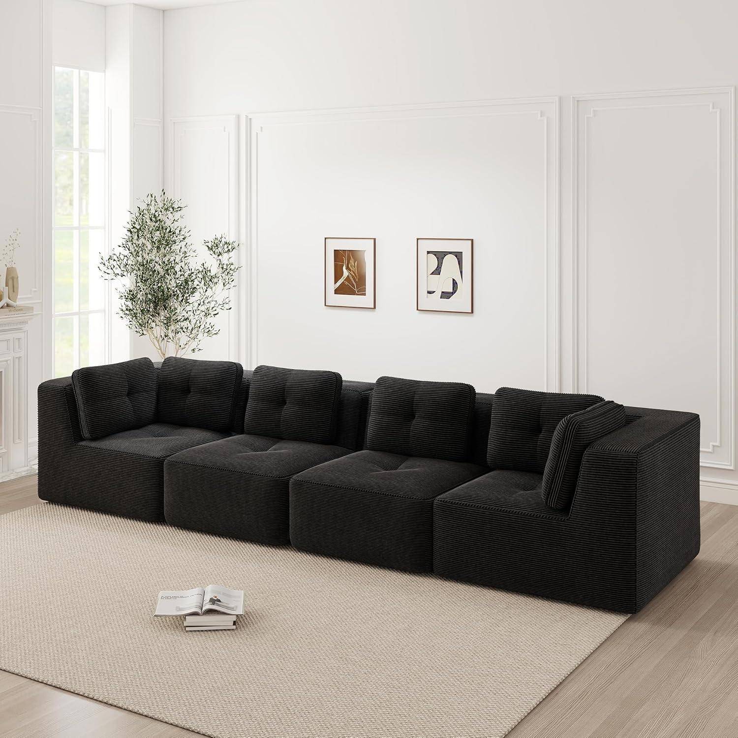 Schwarzes modulares Sofa in einem hellen, minimalistischen Wohnzimmer mit Wandkunst im Rahmen, einer Pflanze und einem aufgeschlagenen Buch auf einem beigefarbenen Teppich.