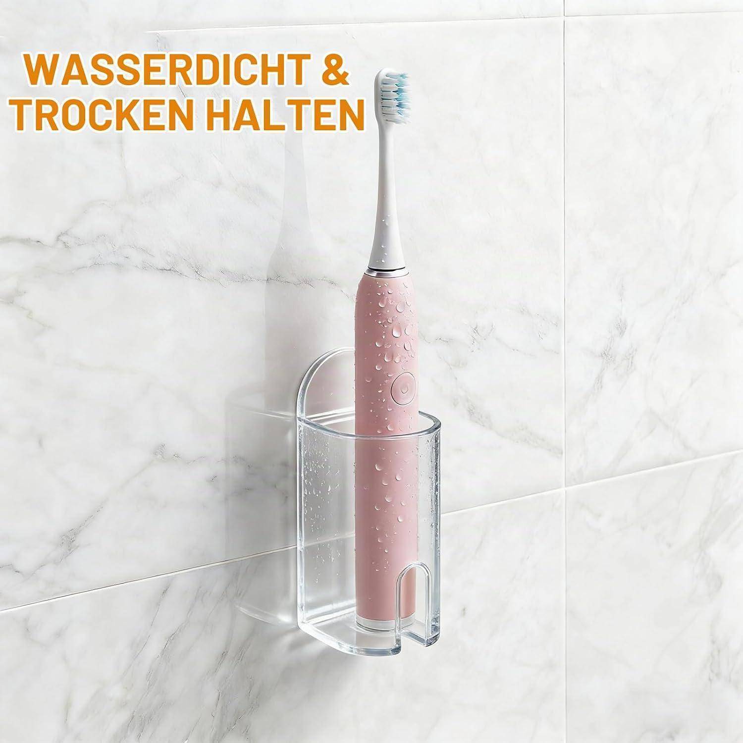 Rosa elektrische Zahnbürste in einem durchsichtigen wandmontierten Behälter an einer gefliesten Badezimmerwand, mit deutschem Text „WASSERDICHT & TROCKEN HALTEN