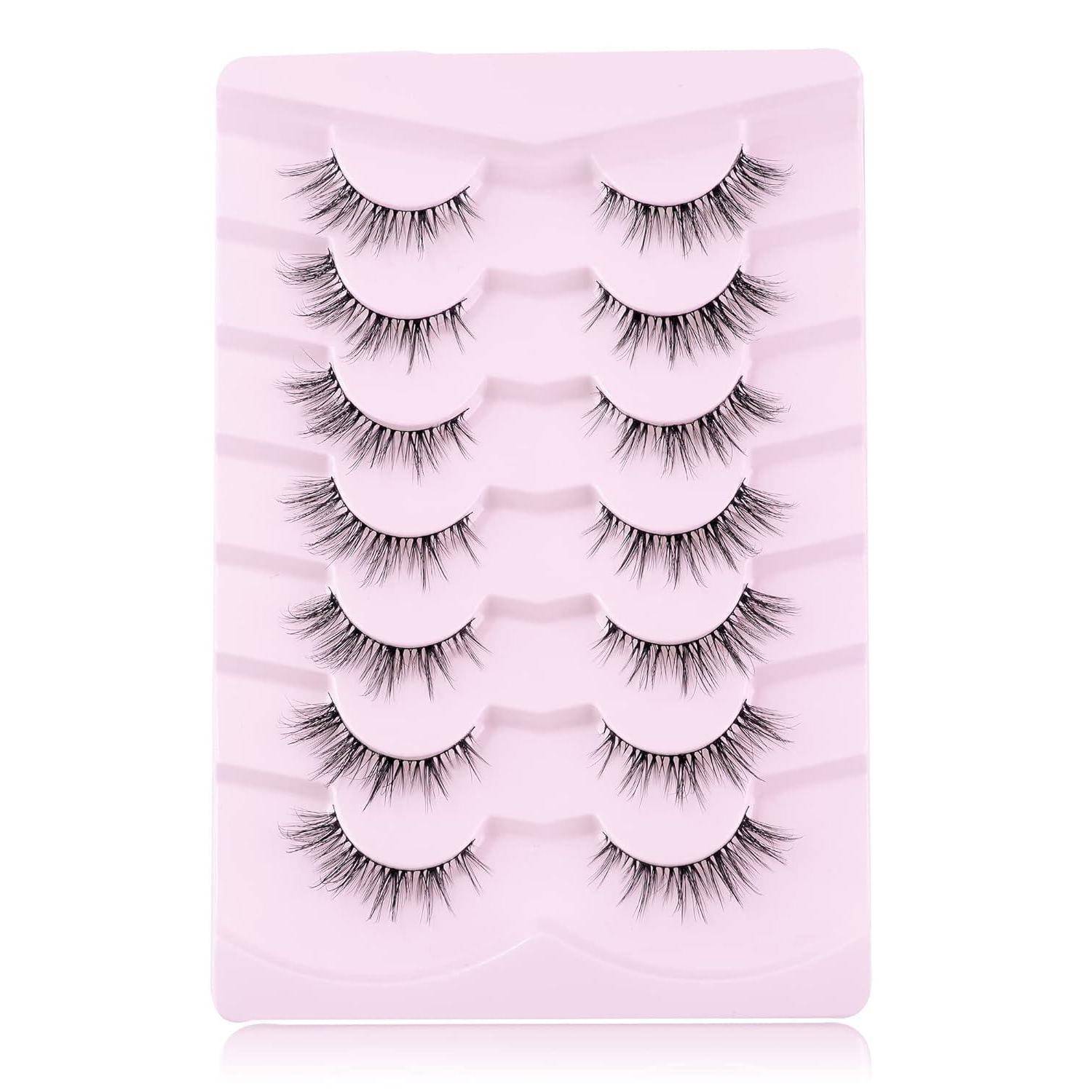 Packung mit sechs Paar künstlichen Wimpern, die auf einem rosa Tablett in zwei vertikalen Spalten angeordnet sind.