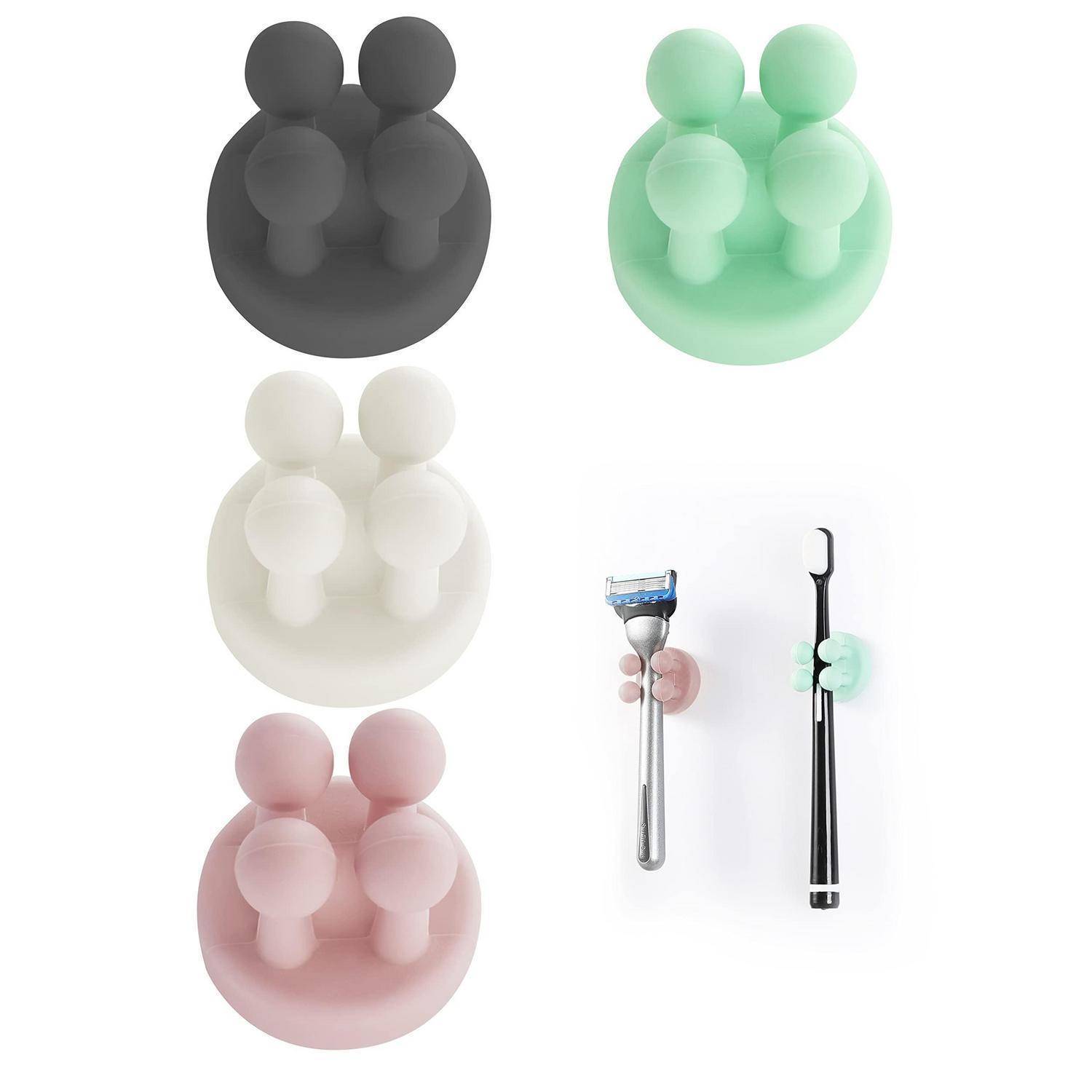 Vier Silikonhalter in Schwarz, Mint, Weiß und Rosa; jeder greift zwei kleine Gegenstände. Einer hält einen Rasierer, der andere ein schwarzes stabförmiges Werkzeug.