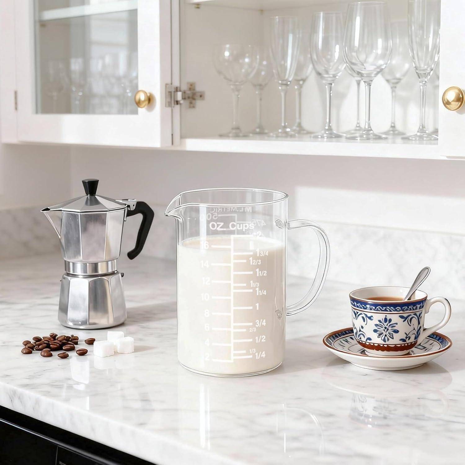 Kaffee-Zubereitungseinrichtung auf einer Marmorarbeitsplatte: Stovetop-Moka-Kanne, Milch in einem Messbehälter, Espressotasse und Untertasse, Bohnen und Zuckerwürfel in einer hellen Küche.