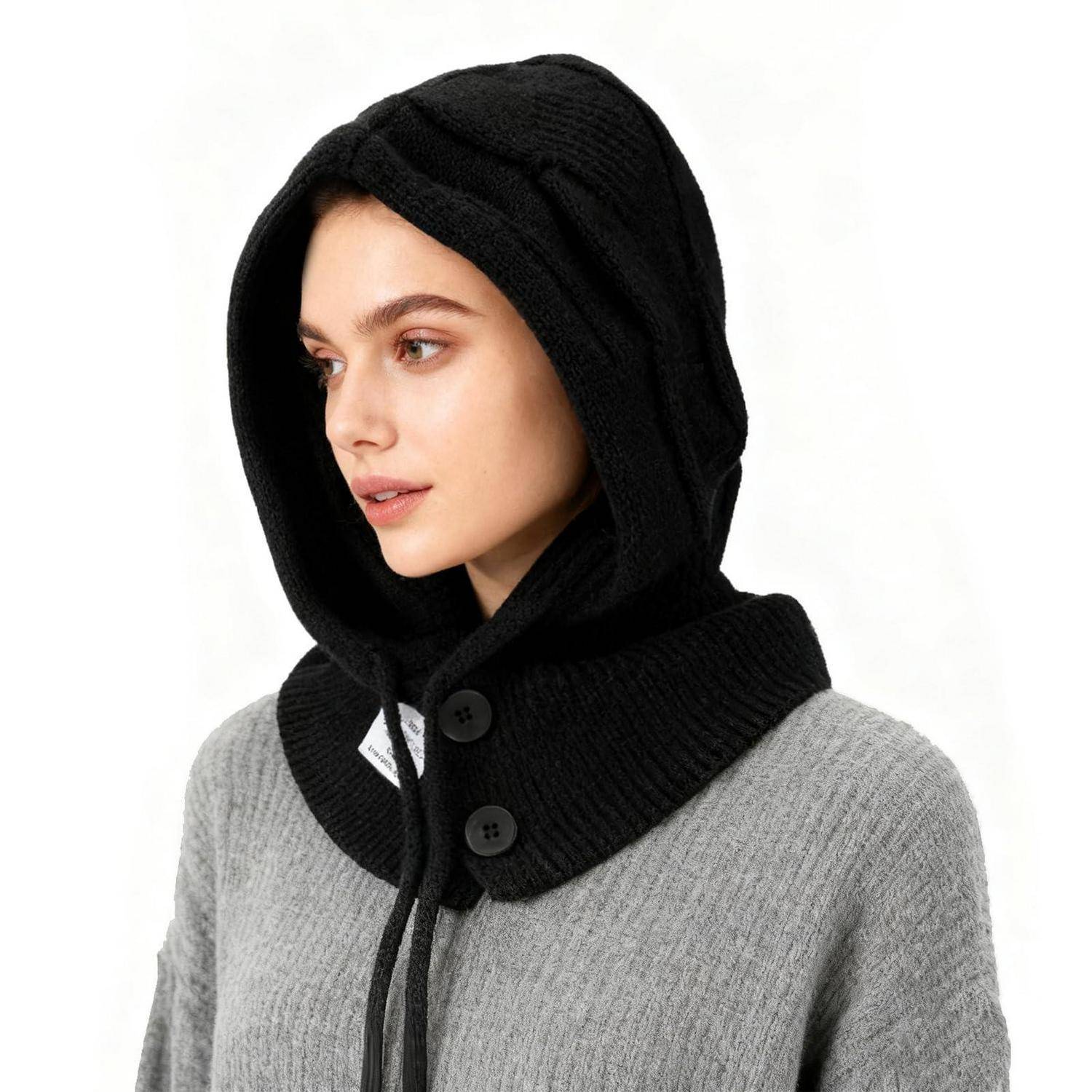 Porträt einer Frau, die einen schwarzen gestrickten Kapuzenschal über einem grauen Pullover vor einem einfachen weißen Hintergrund trägt.