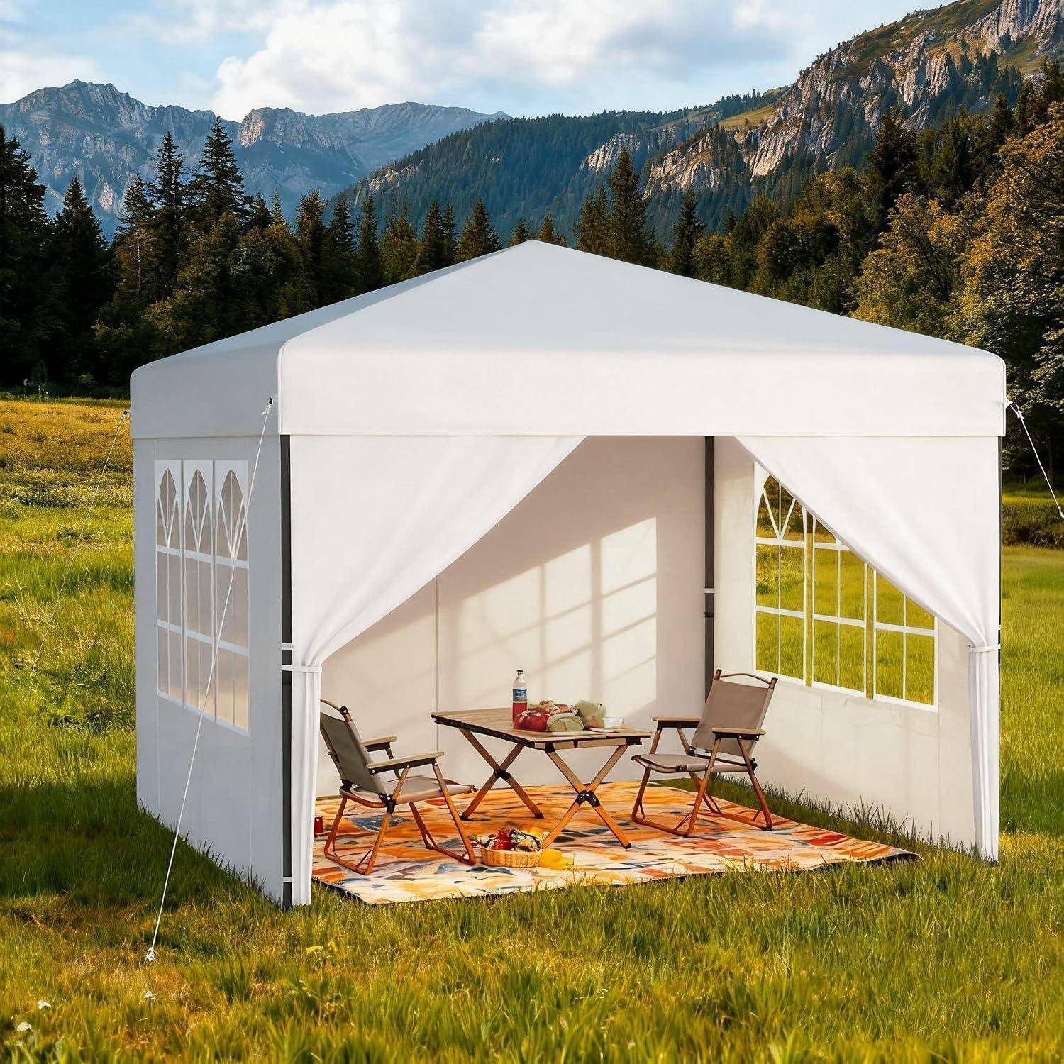 Weißes Outdoor-Pavillon-Zeltset mit zwei Klappsesseln, einem kleinen Tisch und einem Teppich, aufgebaut auf einer grasigen Bergwiese.