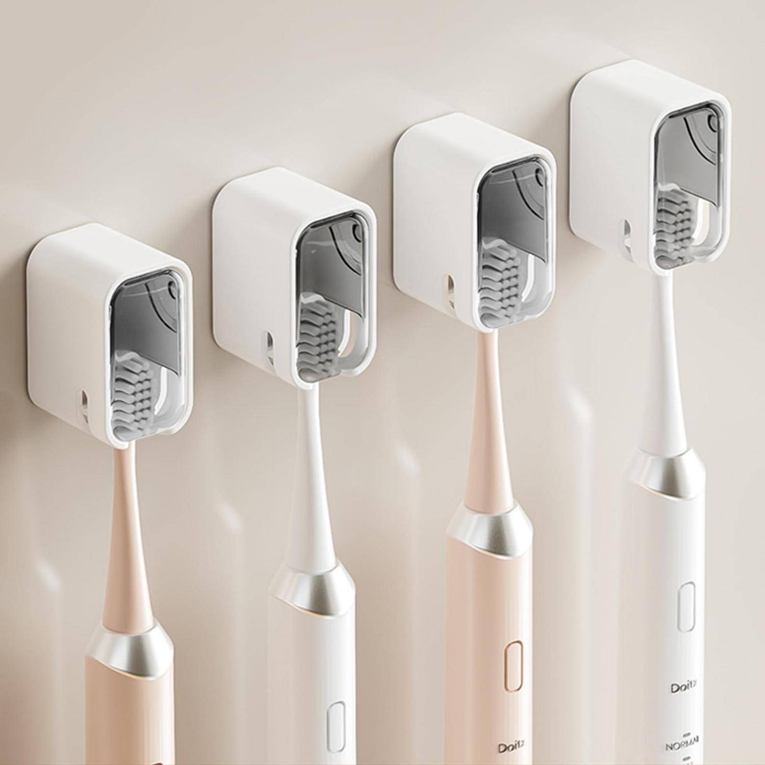 Vier elektrische Zahnbürsten in wandmontierten Haltern, in Weiß, Beige und Rosa gezeigt, in einer Reihe auf einer hellen Wand angeordnet.