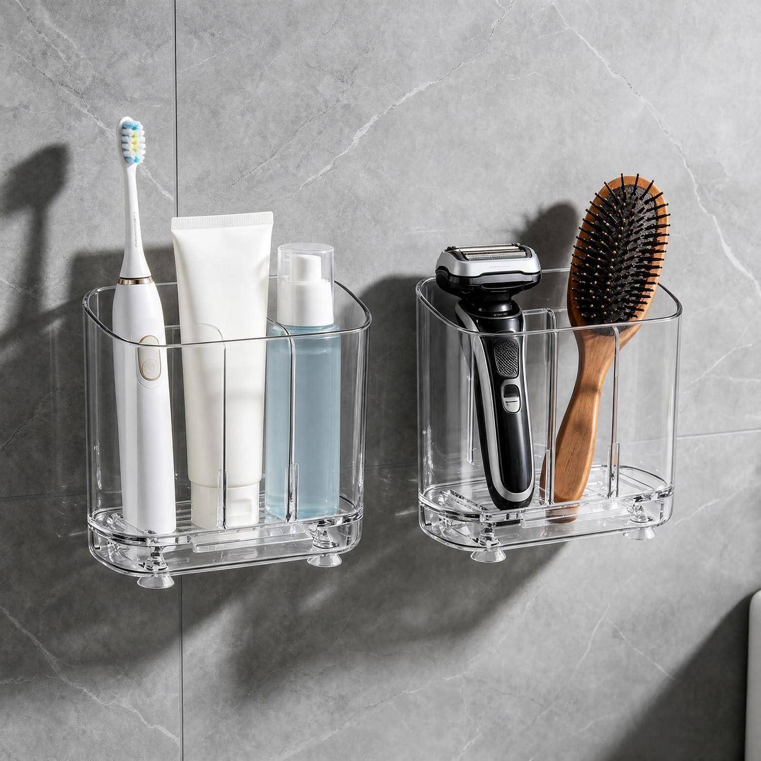 Zwei transparente, wandmontierte Badezimmerorganizer halten auf der linken Seite eine Zahnbürste, eine Tube und eine Flasche und auf der rechten Seite einen elektrischen Rasierer und eine Haarbürste.