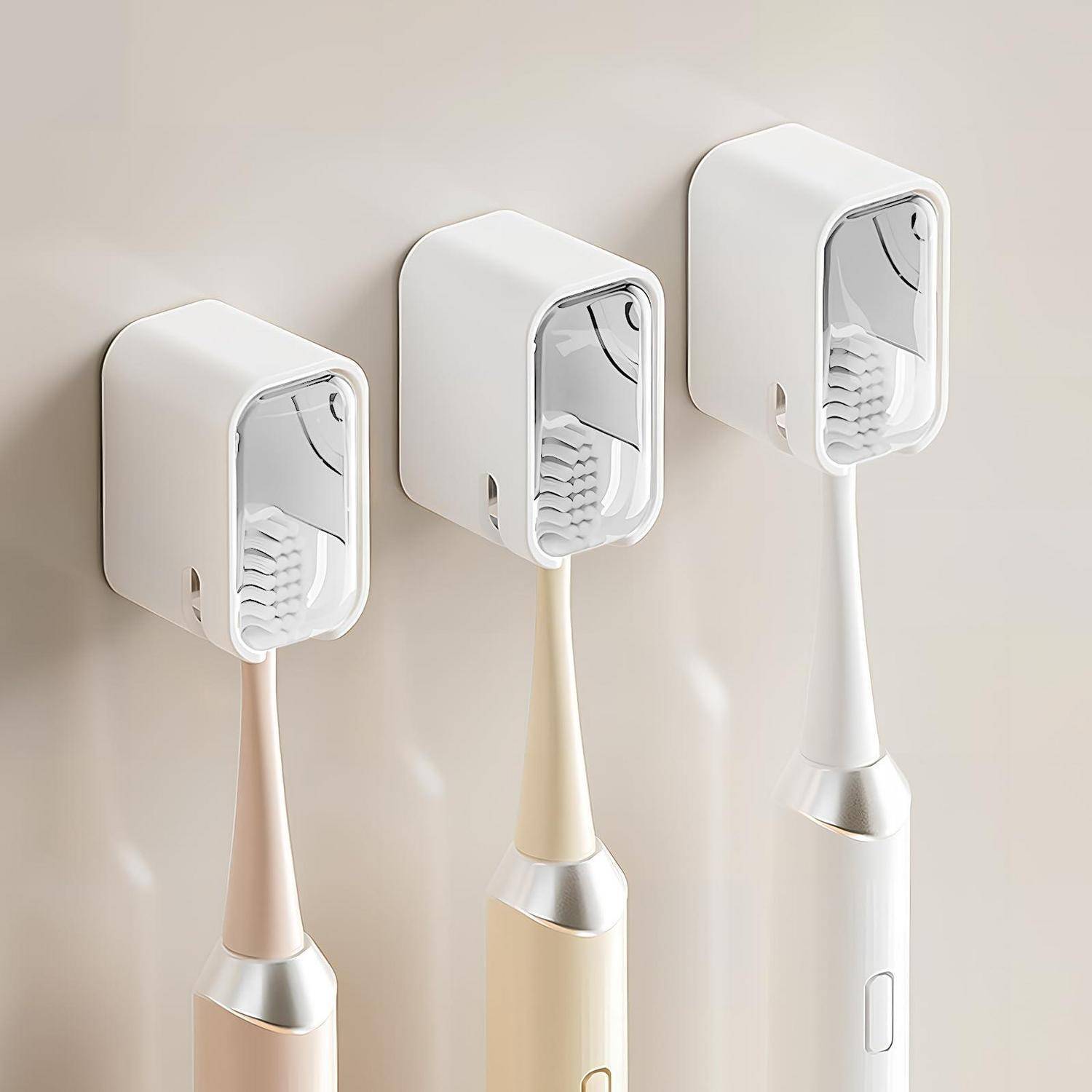 Drei wandmontierte elektrische Zahnbürsten in Pastellfarben sind in Ladeholtern gegen eine beigefarbene Wand angedockt.