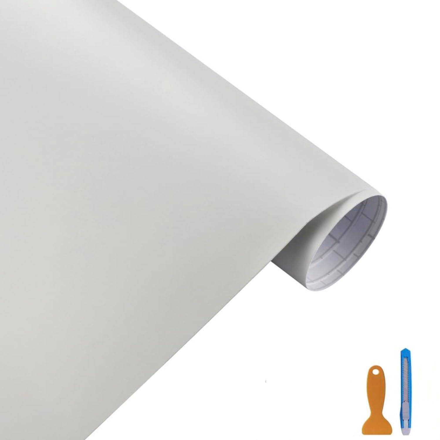 Rolle aus grauem Klebevinyl oder Kontaktpapier, teilweise abgerollt, mit einem kleinen blauen Universalmesser und einem orangen Schaber unten rechts.