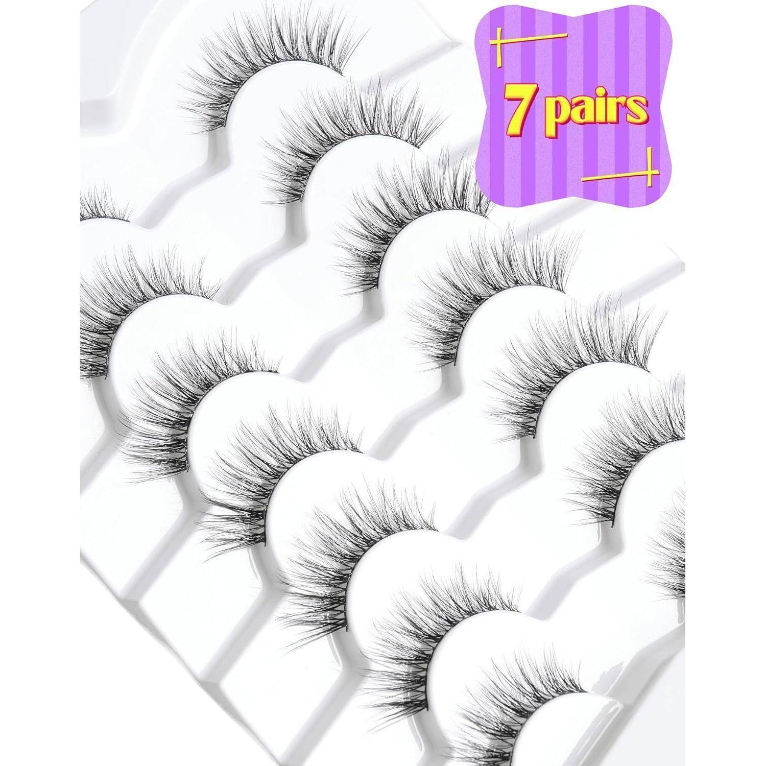 Produktbild von sieben Paar langen, flauschigen künstlichen Wimpern, angeordnet auf weißen Tabletts, mit einem lila Etikett, auf dem „7 Paar