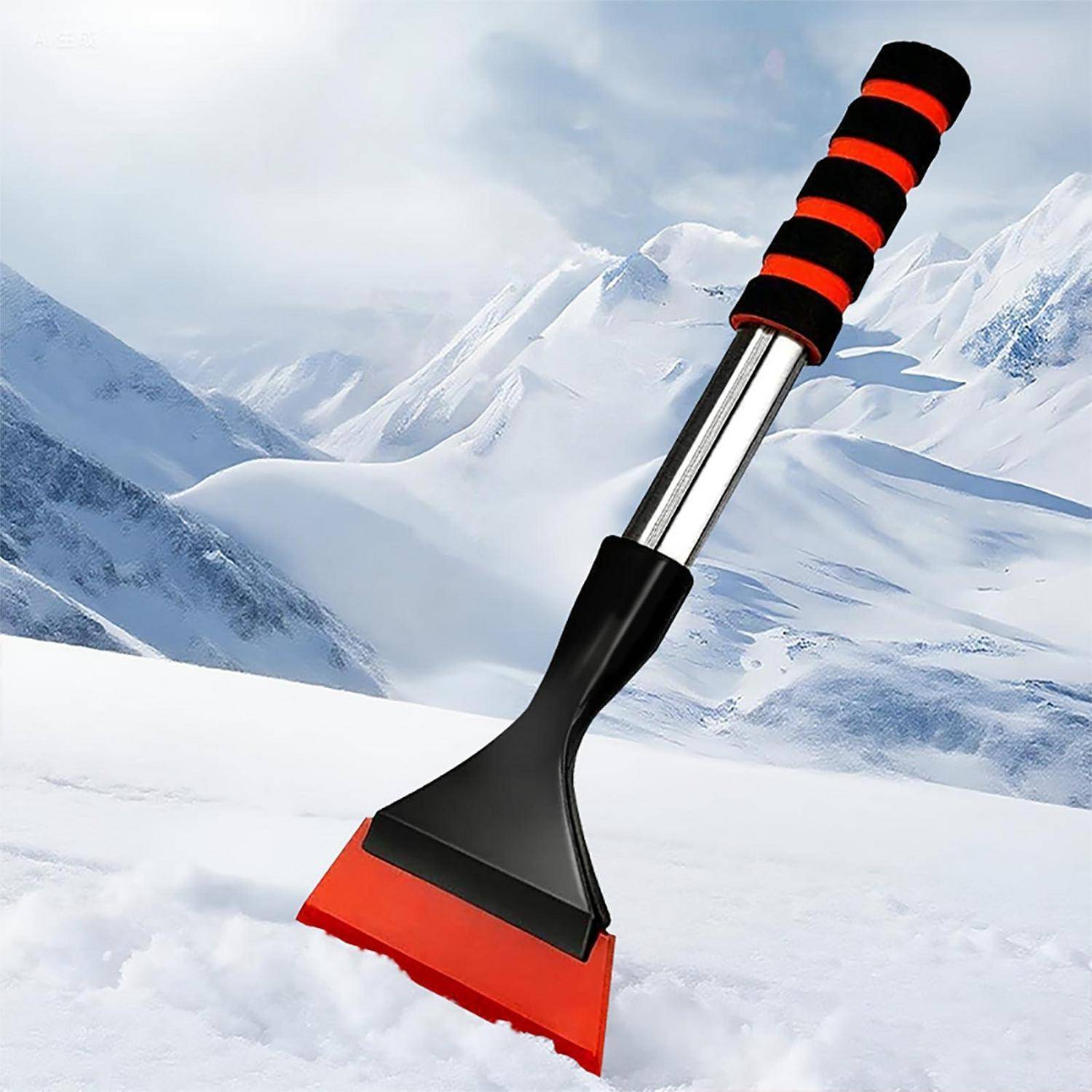 Rot-schwarzer Eiskratzer mit gestreiftem Griff, der im Schnee steht, vor einem schneebedeckten Berggrund.