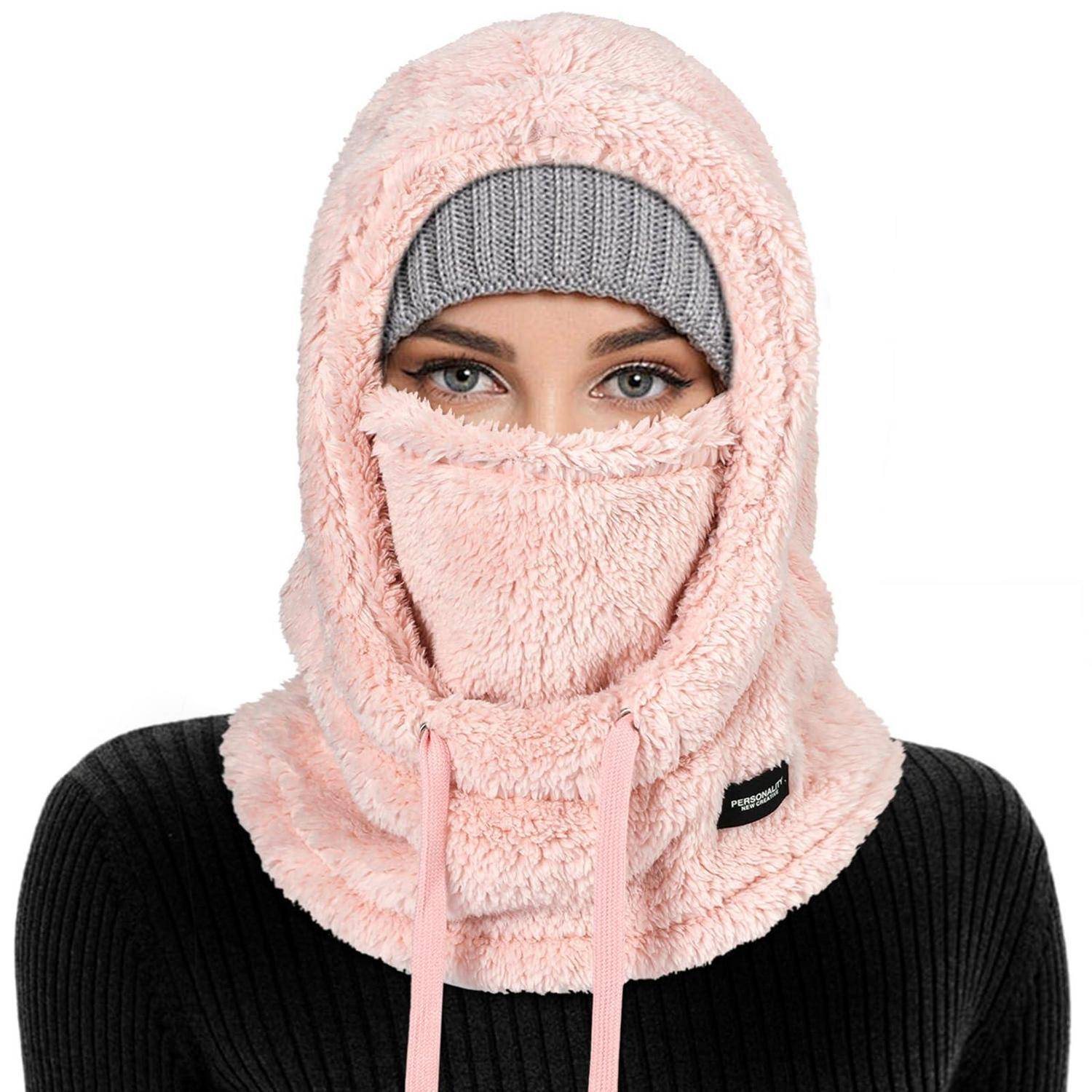 Frau, die eine rosa Fleece-Sturmhaube und eine graue Strickmütze trägt, mit nur ihren Augen, die über einem schwarzen Pullover sichtbar sind.
