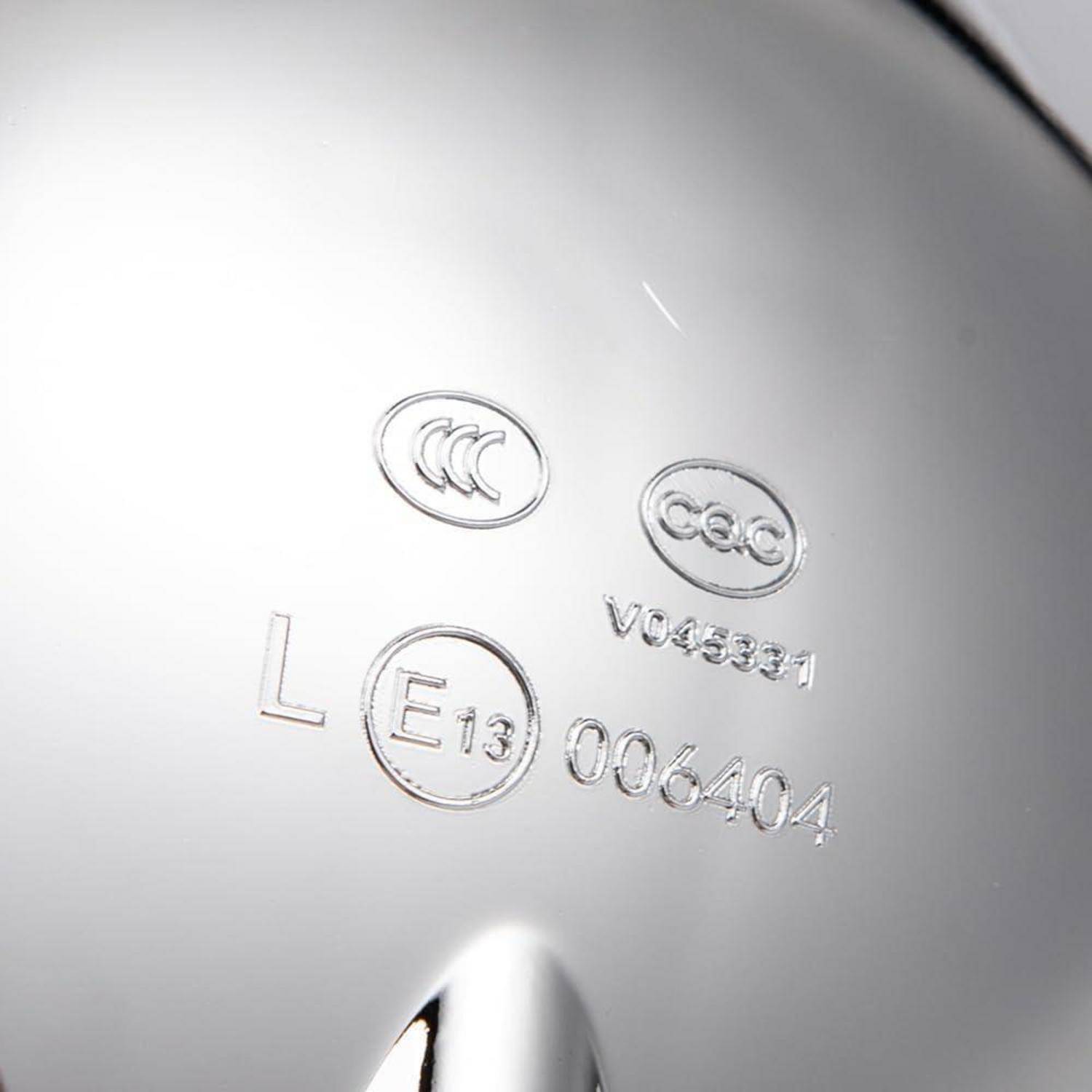 Nahaufnahme des Gehäuses eines weißen Außenspiegels eines Autos mit geprägten Zertifizierungsmarken und Codes, einschließlich 'CCC', 'E13', 'V045331' und '006404'.
