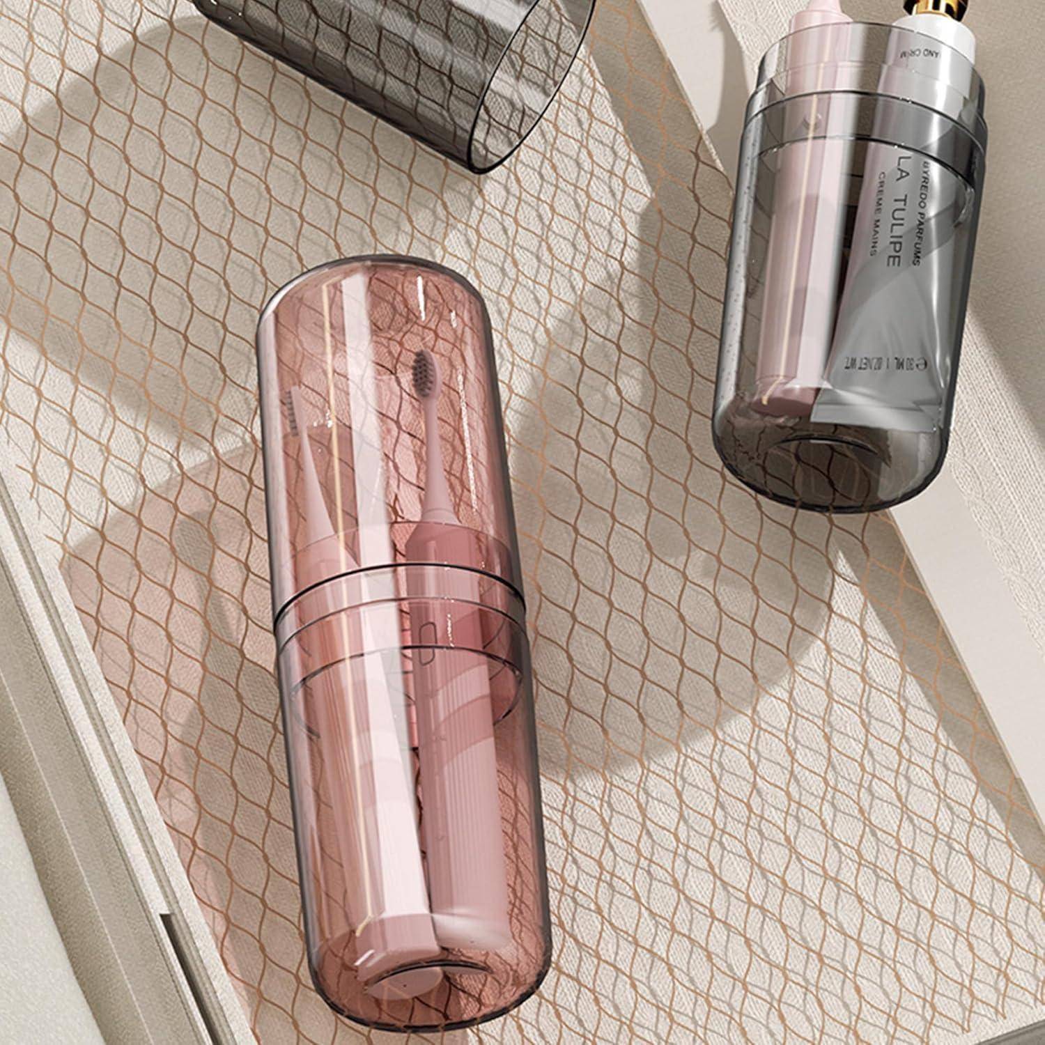 Drei zylindrische Kosmetiktuben in rosa, transparenter und dunkelgrauer Verpackung sind auf gemustertem Stoff angeordnet und deuten auf eine Produktpräsentation oder ein Verpackungsdesign hin.