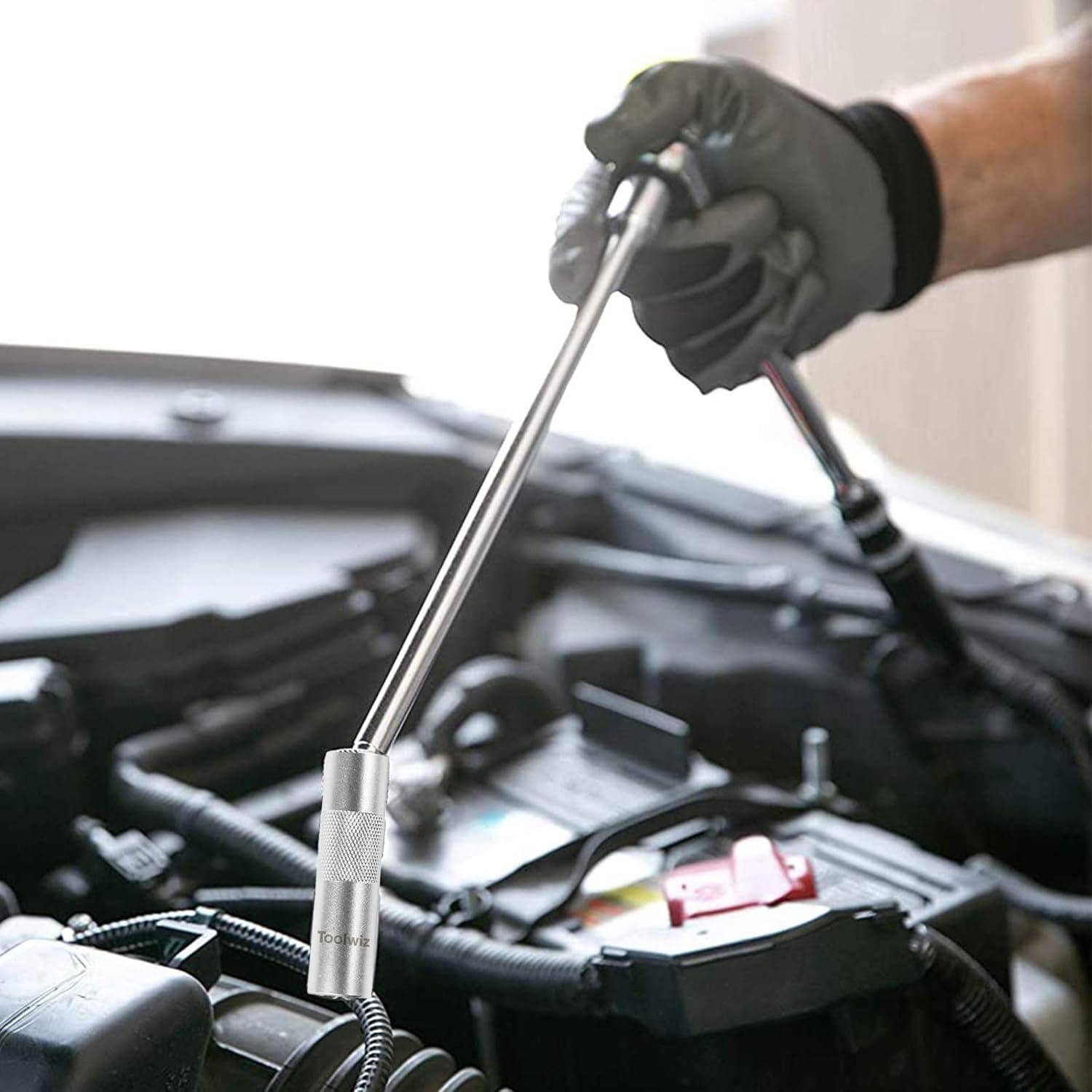 Mit Handschuh bekleidete Hand, die einen langen Steckschlüssel verwendet, um an einem Automotor in dem offenen Motorraum zu arbeiten.