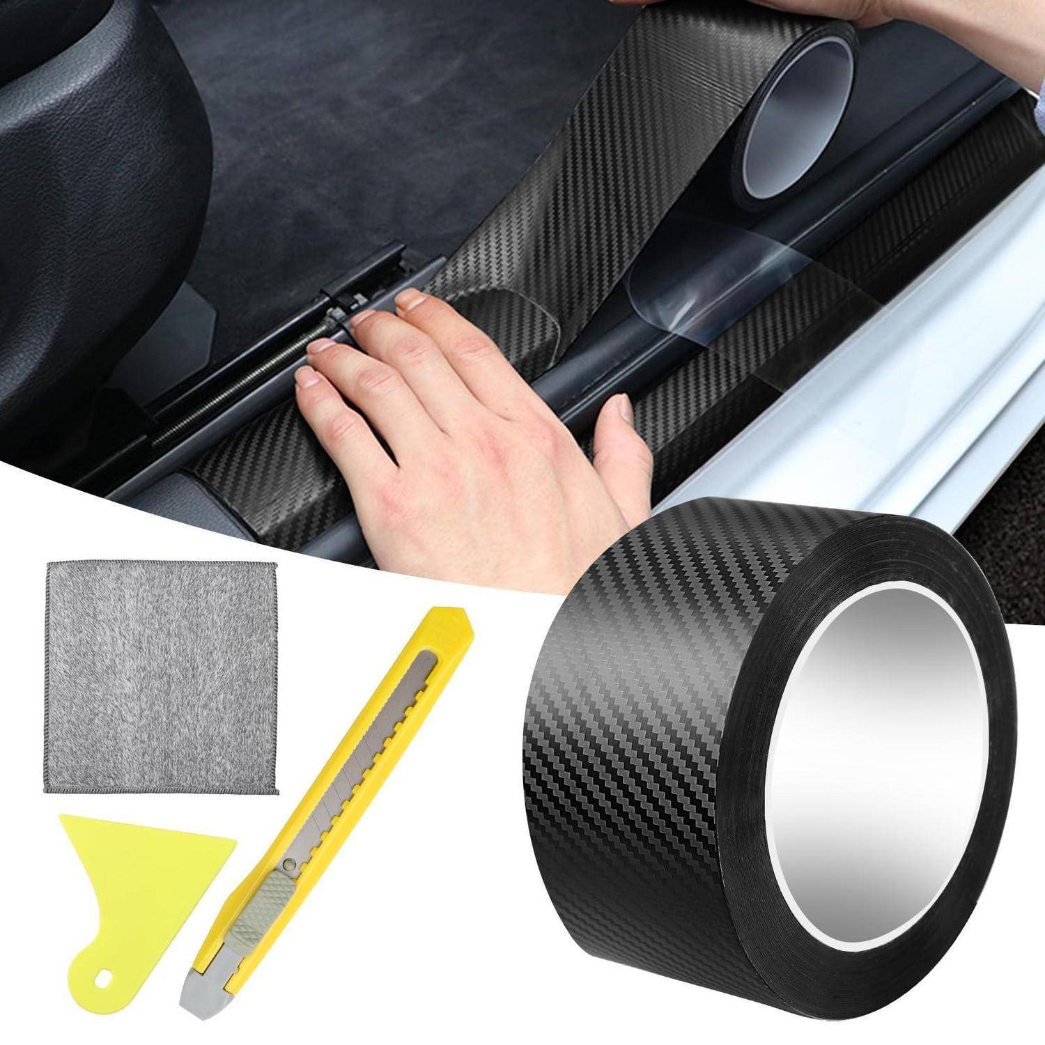 Hand beim Installieren einer schwarzen Kohlefaser-Folie auf einer Autoinnenausstattung, mit einer Rolle Folie, einem Universalmesser und einem Glättungswerkzeug, die unten gezeigt sind.